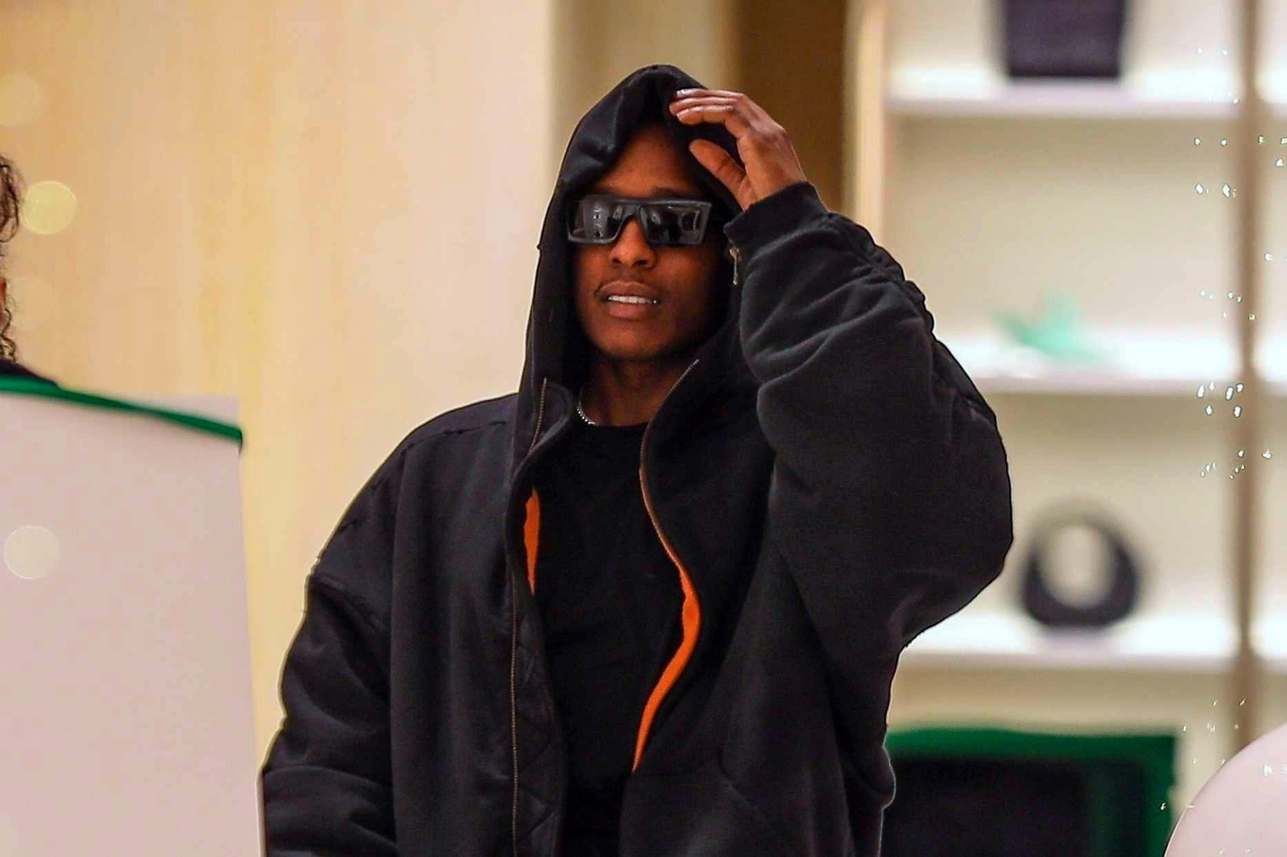 Asap Rocky wears black sunglasses, a leather jacket, Supreme sweatpants, and PUMA sneakers at the Bottega Veneta store in los Angeles