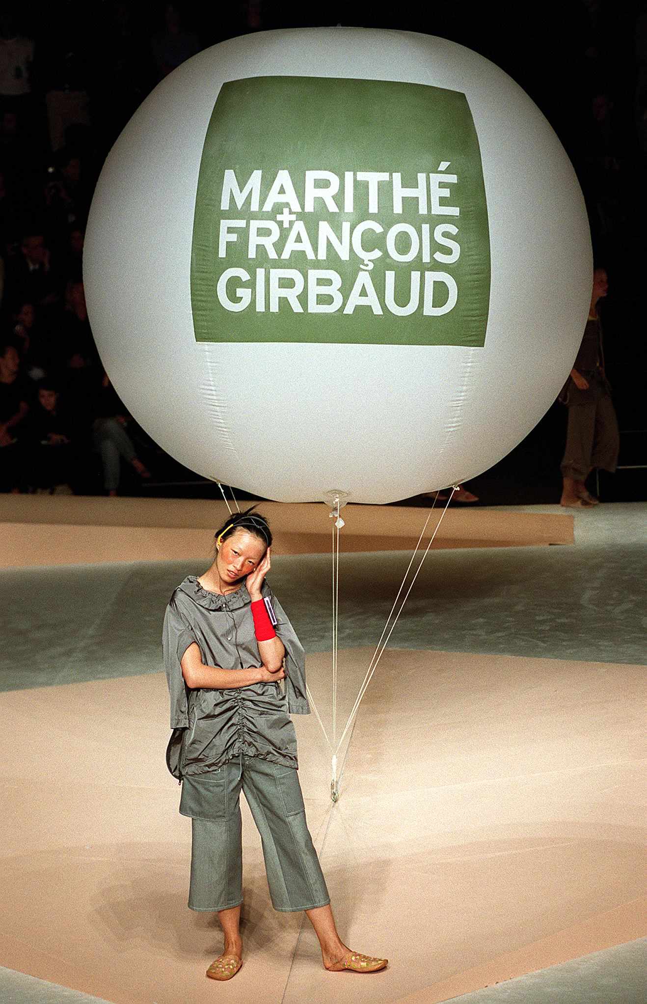 A model poses with a large white balloon with a green Marithe + Francois Girbaud logo