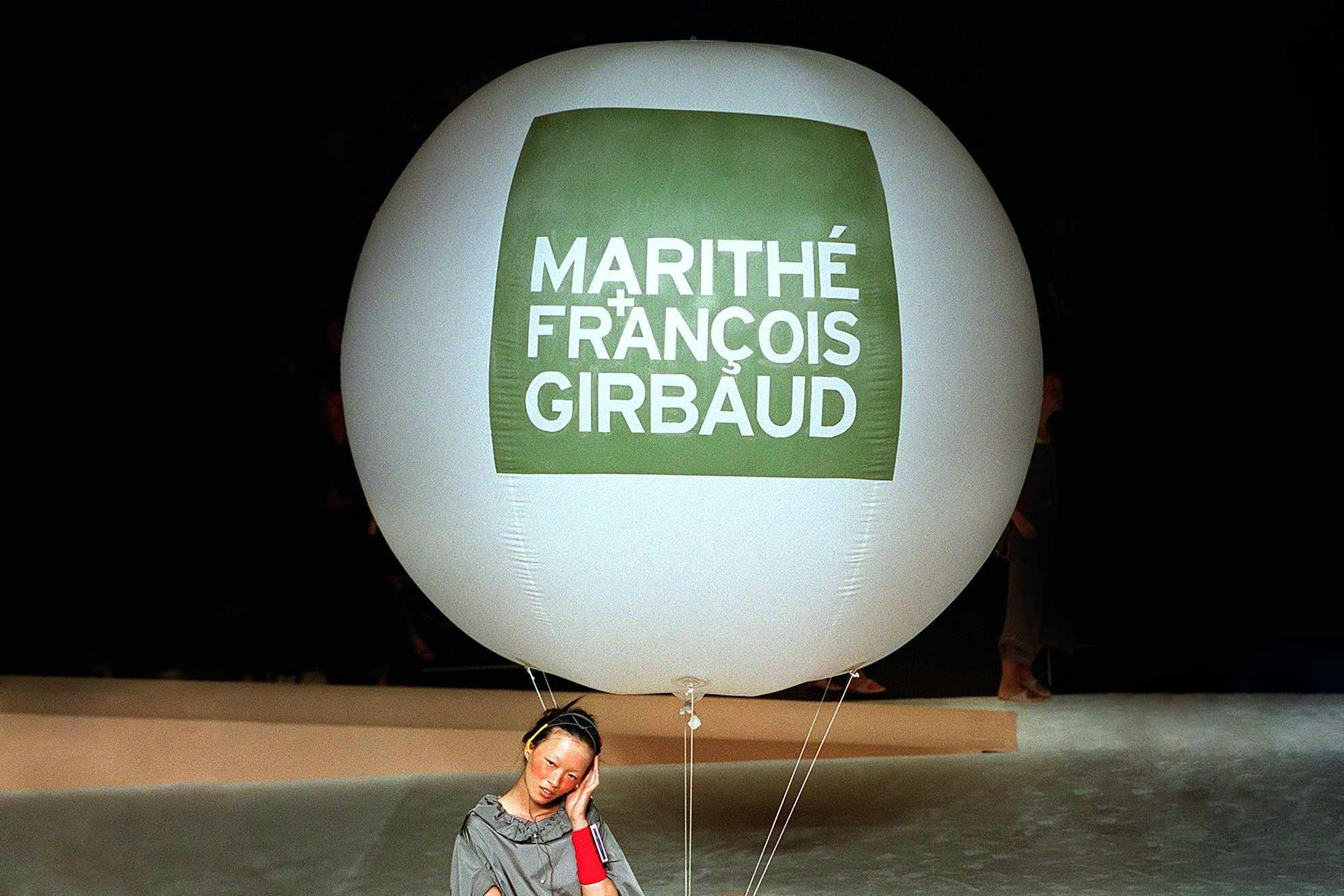 A model poses with a large white balloon with a green Marithe + Francois Girbaud logo