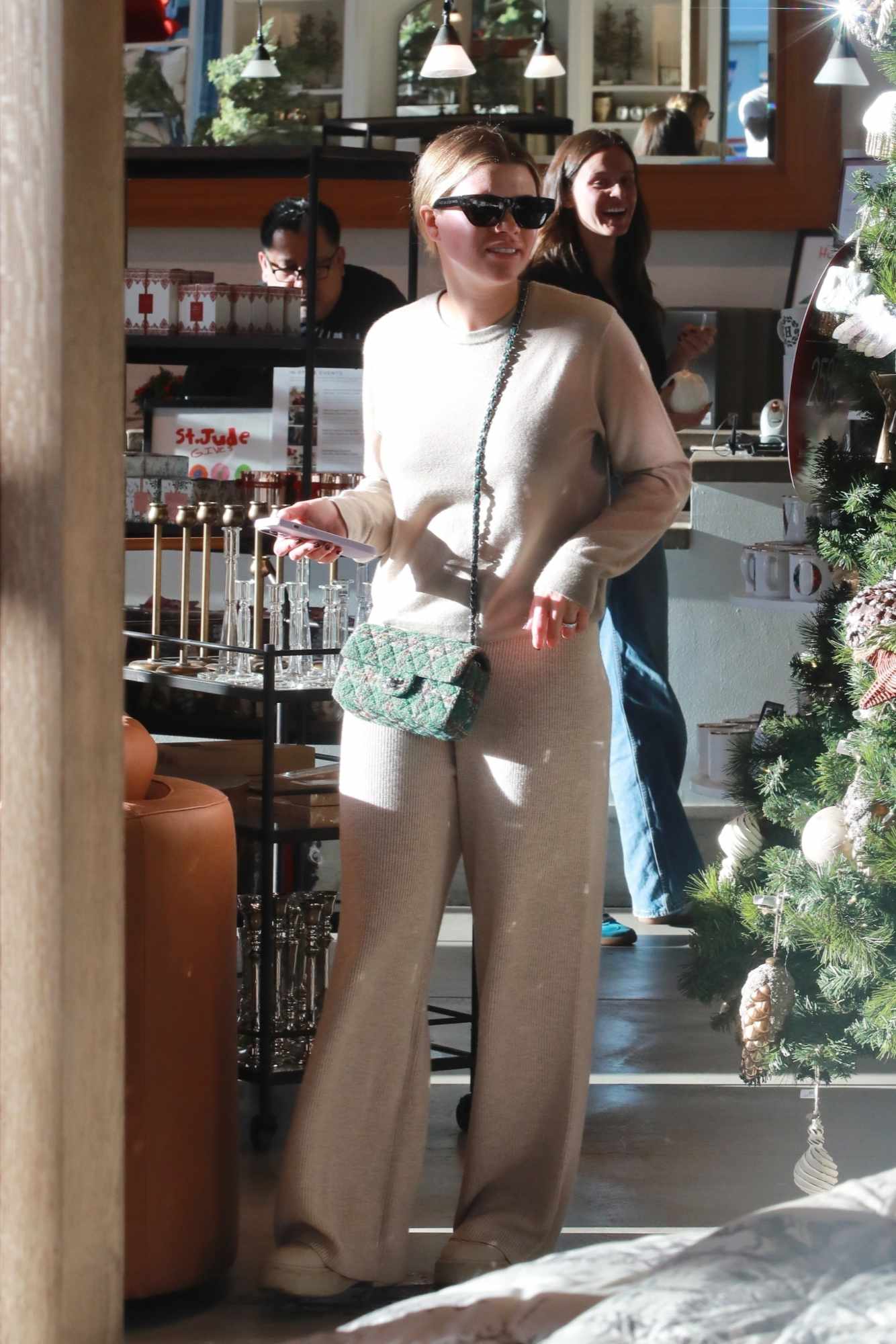 Sofia Richie wears black sunglasses, a Chanel bag, and a beige sweater/sweatpants set at Pottery Barn Beverly Hills