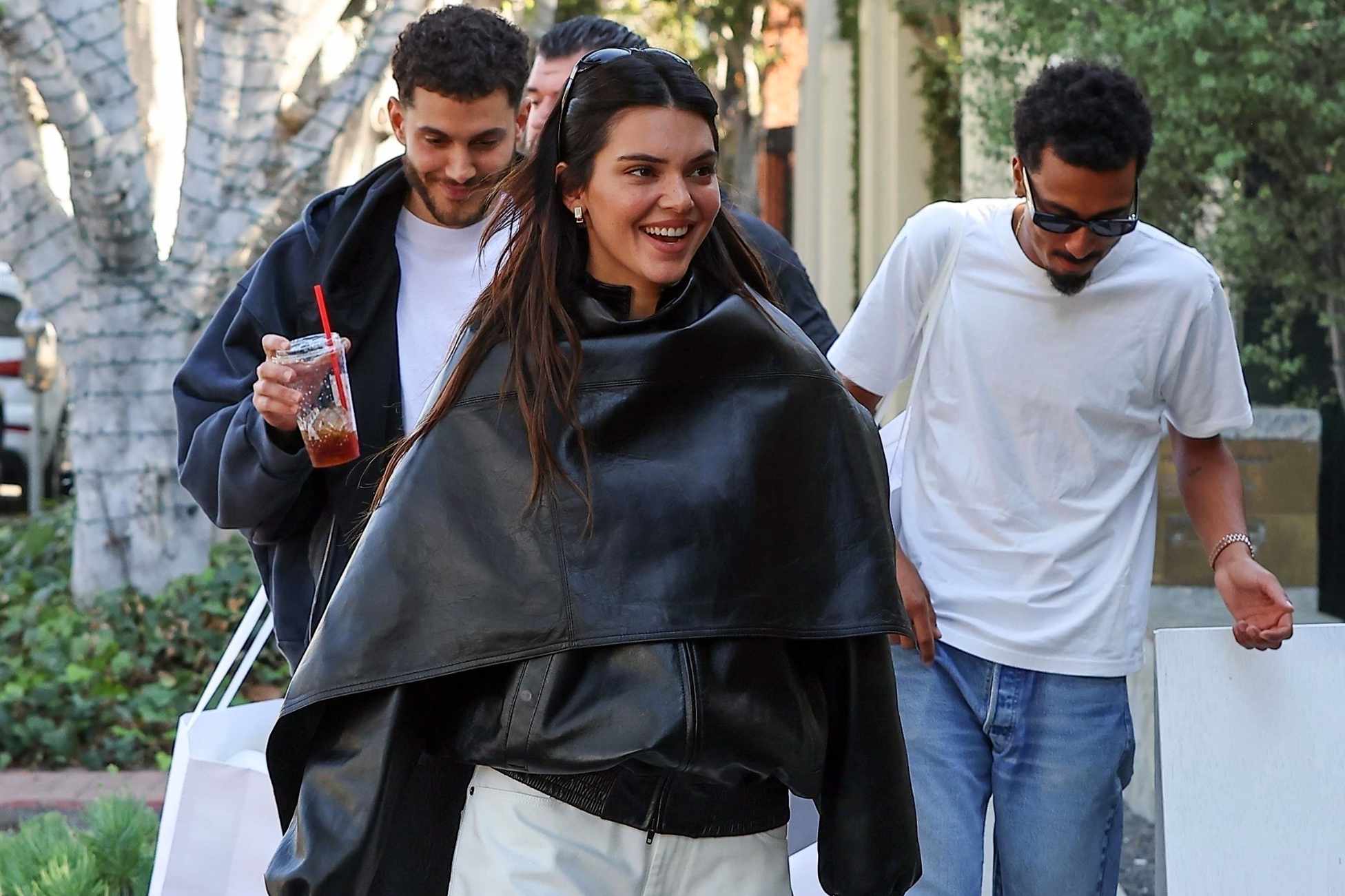 Kendall Jenner wears Phoebe Philo's black leather bomber and cape with wide white pants in December 2023