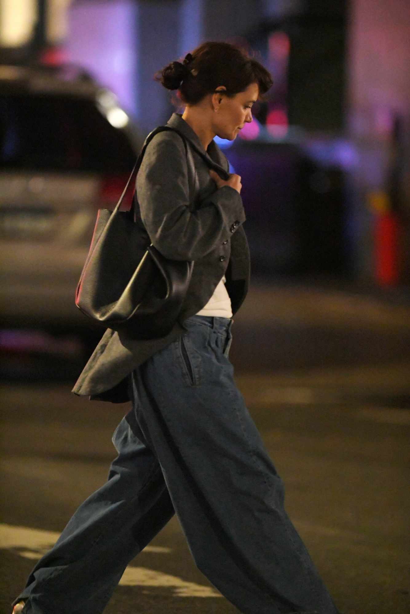 Katie Holmes seen in New York wearing a grey jacket, wide blue jeans, and a brown leather bag