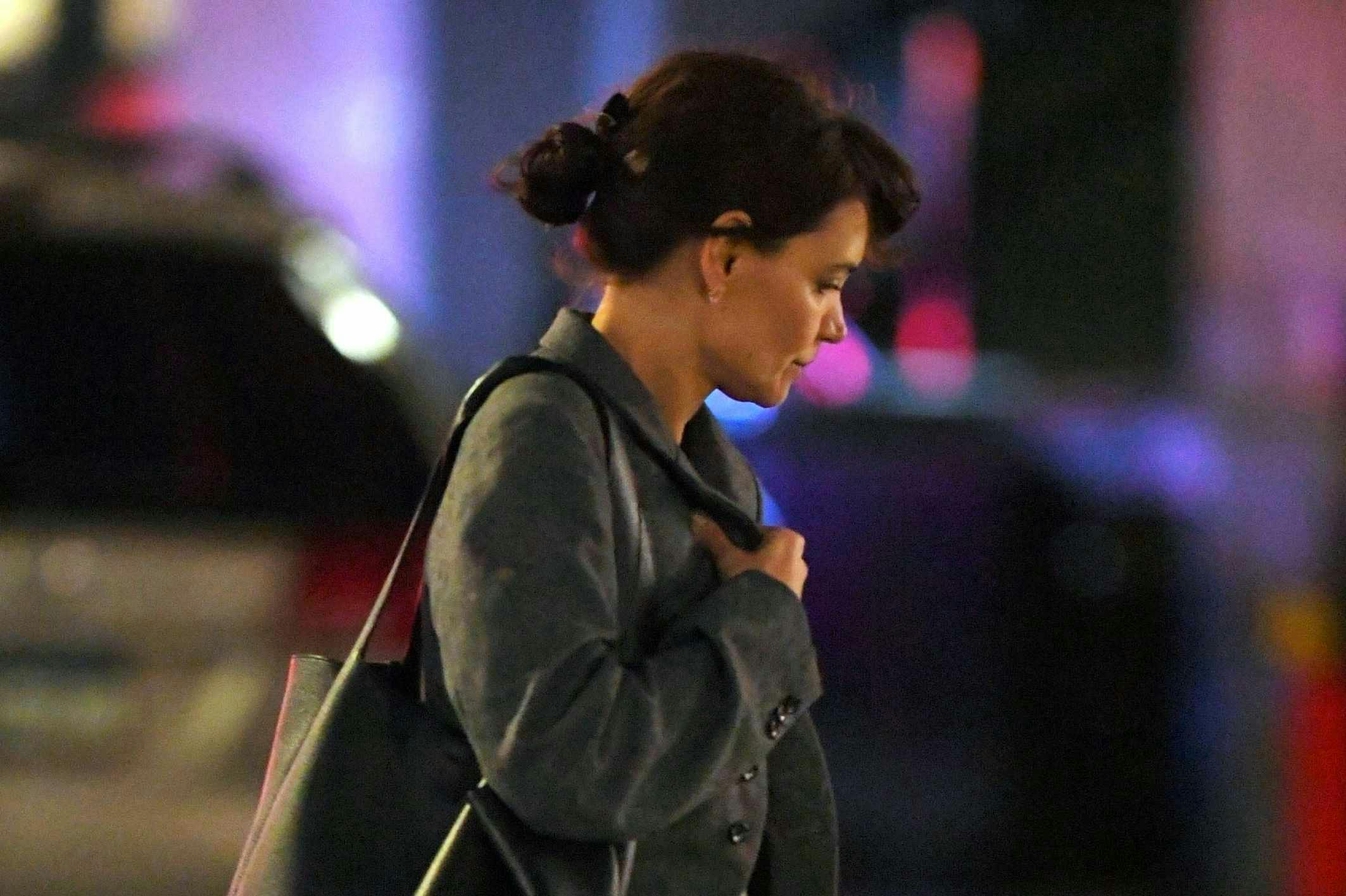 Katie Holmes seen in New York wearing a grey jacket, wide blue jeans, and a brown leather bag