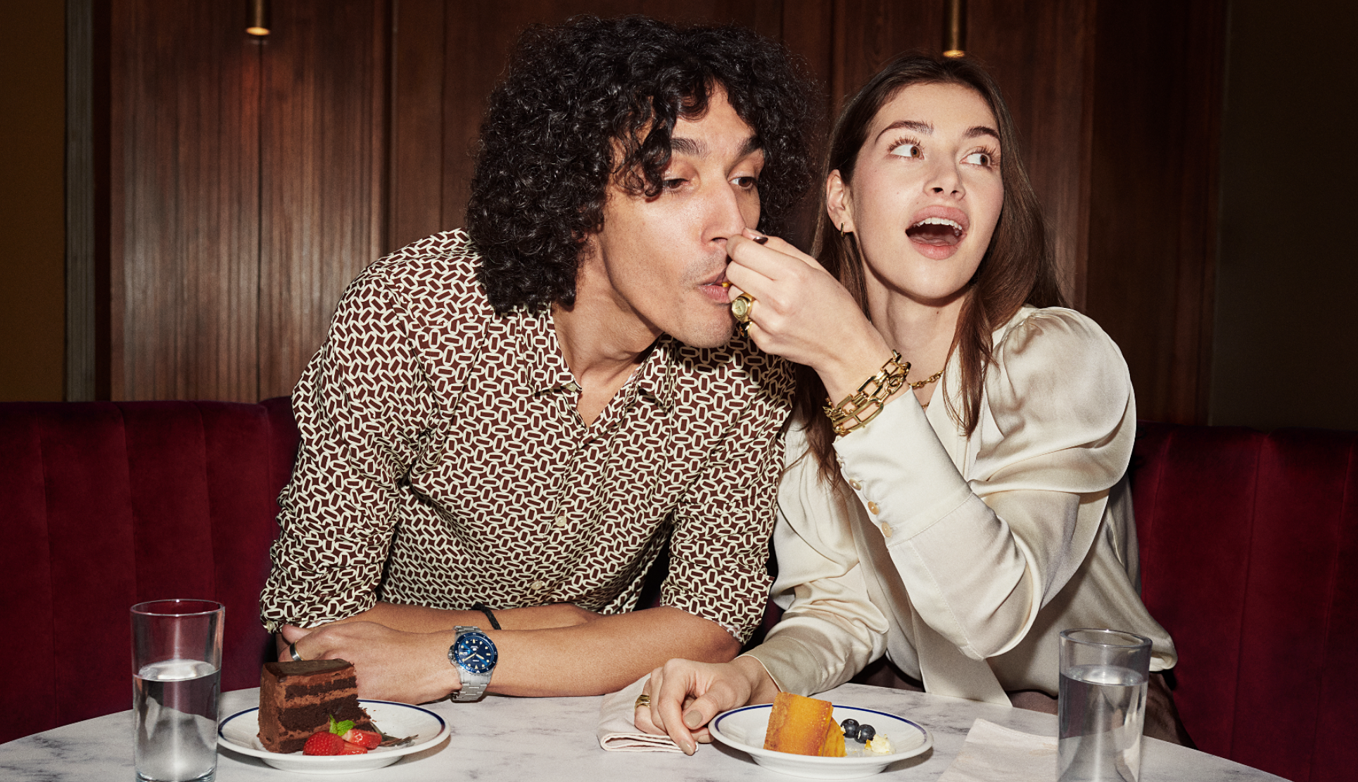 Woman feeding man food at bar while wearing fossil accessories