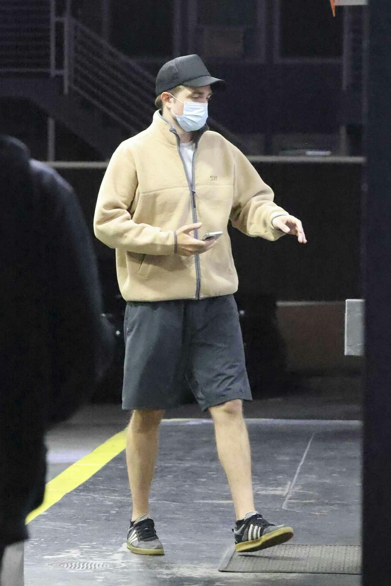 Robert Pattinson wears a beige Kenzo jeans fleece, shorts, and adidas sneakers