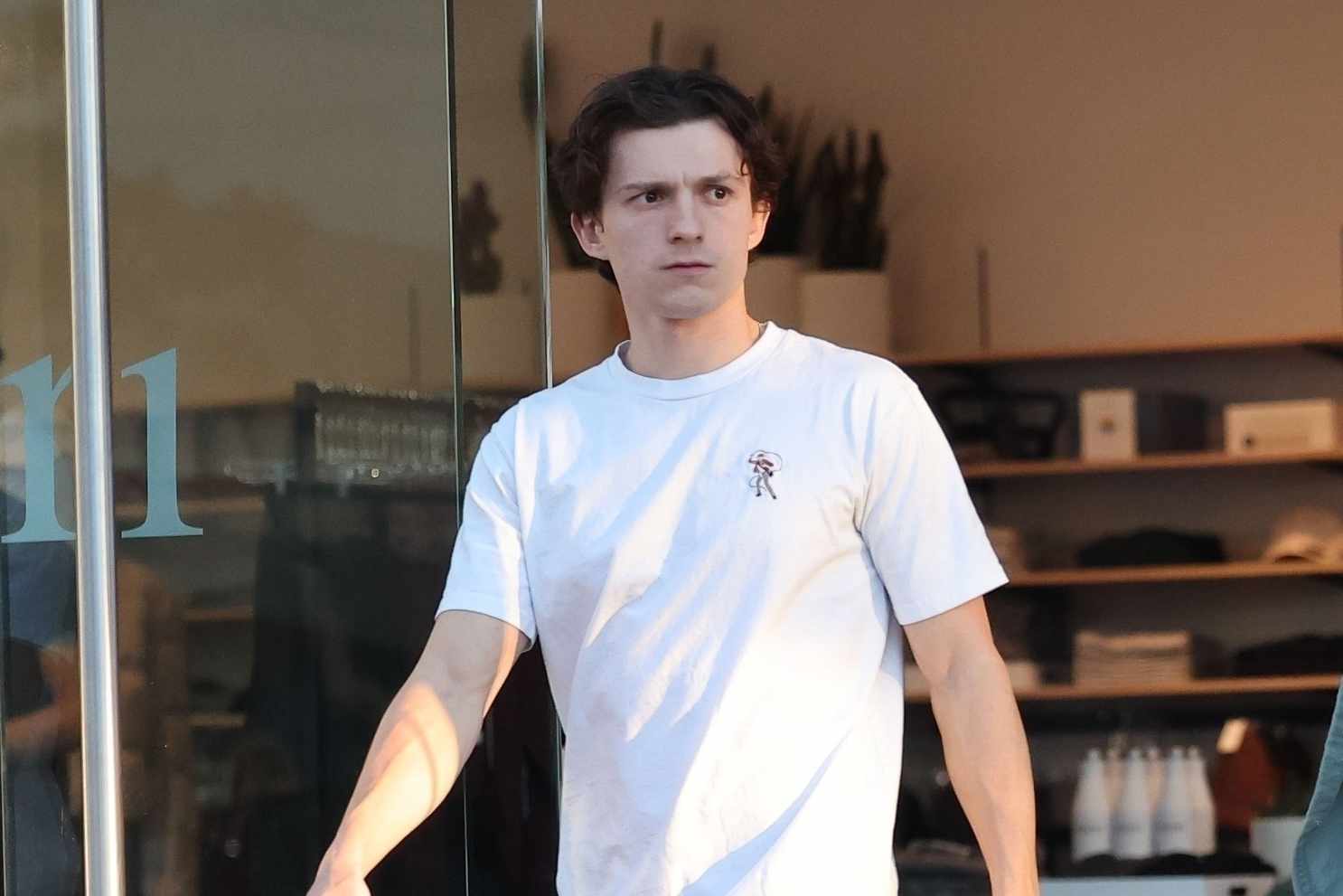Tom Holland wears a white T-shirt and black pants with black leather shoes