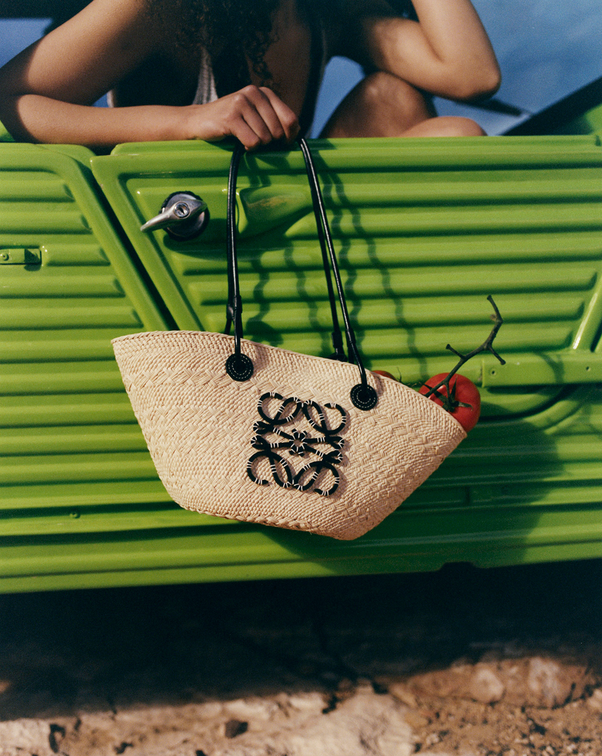 model holding loewe bag with tomates inside, green truck as background