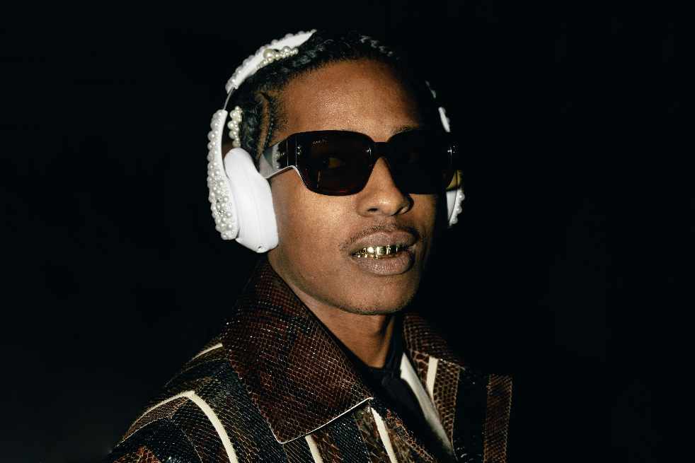A$AP Rocky wears sunglasses, pearl Beats headphones, and a striped Gucci coat