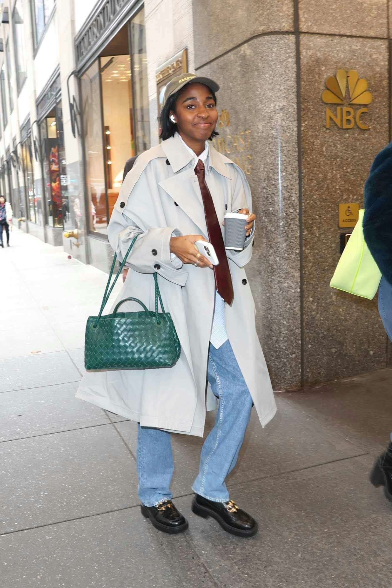 Ayo Edebiri wearing Bottega Veneta's trench coat, shirt, tie, jeans, loafers, and Vendiamo bag