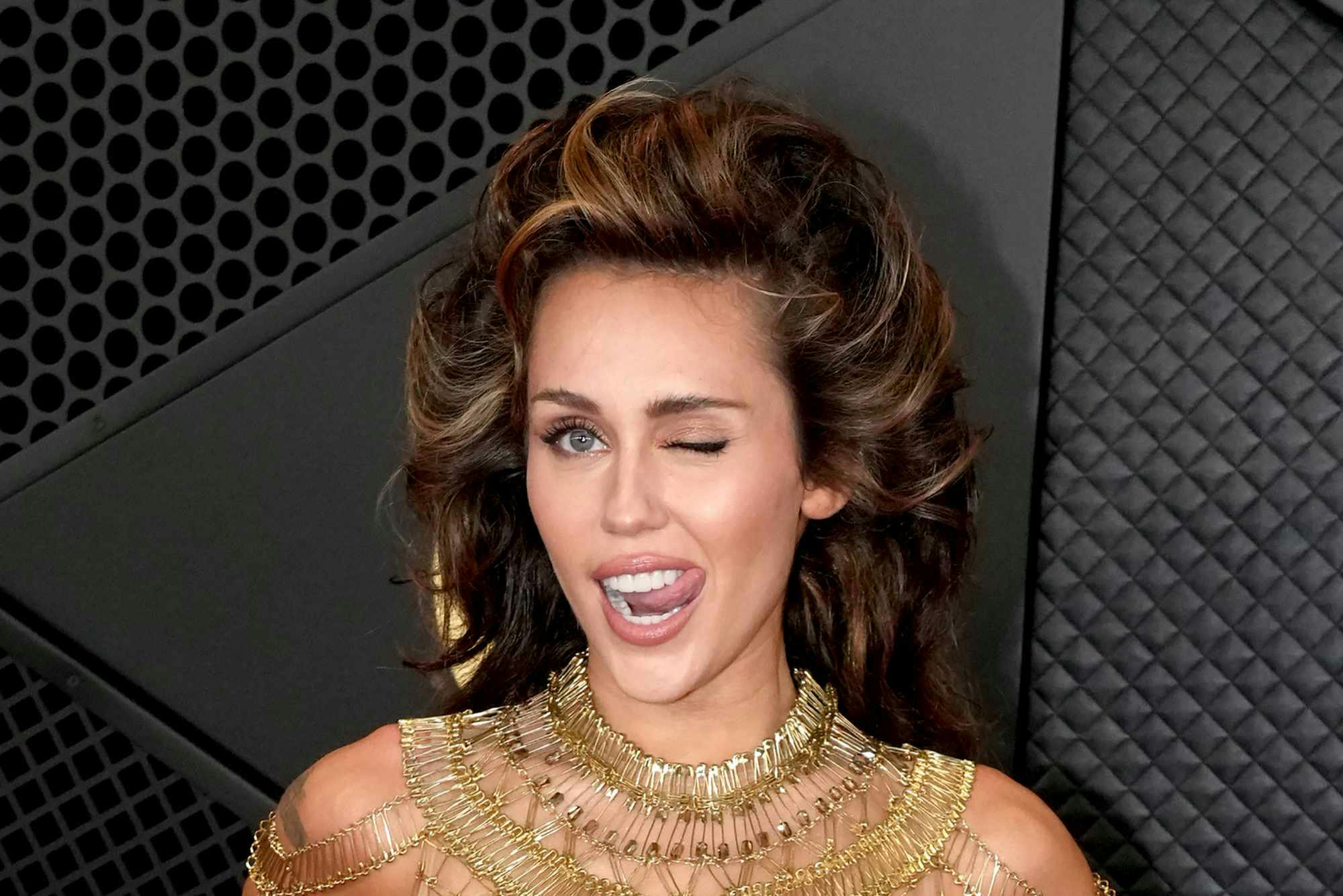 Miley Cyrus wears a gold dress & tall hair at the 2024 Grammy awards