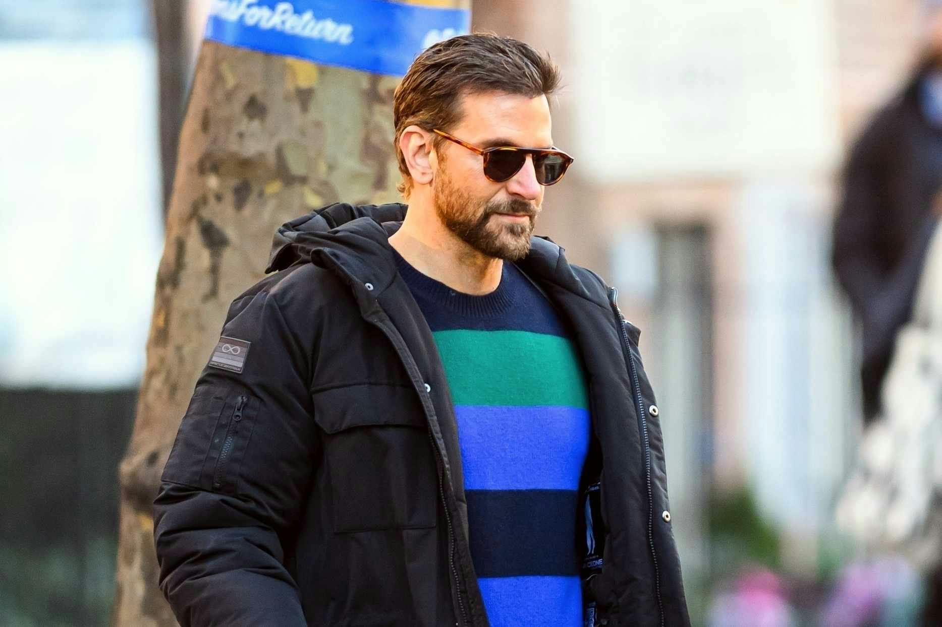 Bradley Cooper wears a Spaceone coat and striped sweater from Gigi Hadid's brand with Salomon sneaker boots