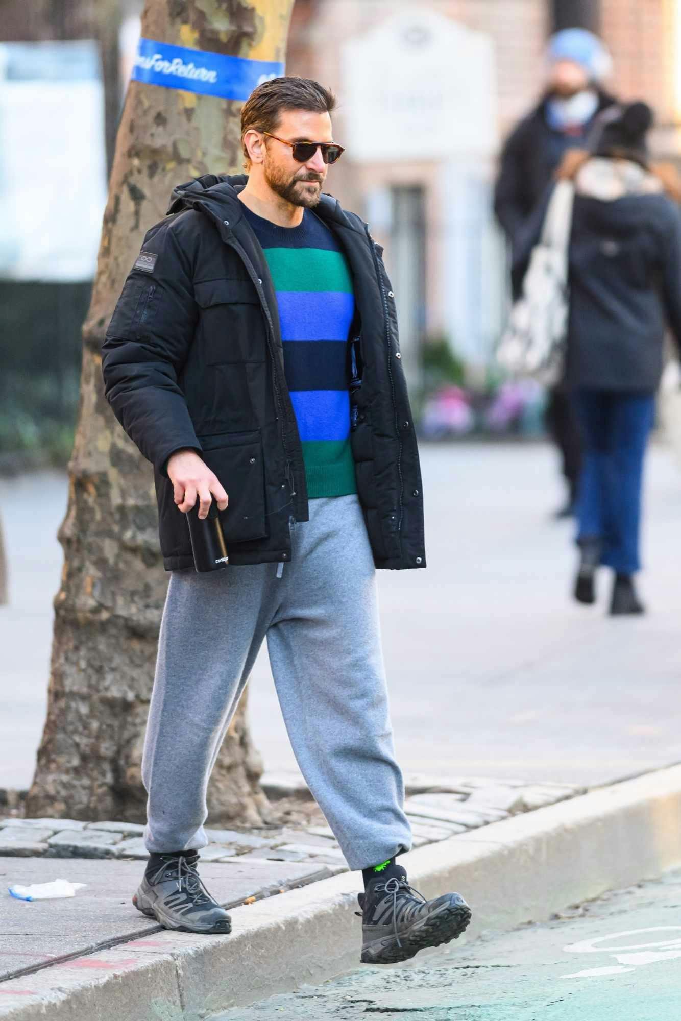 Bradley Cooper wears a Spaceone coat and striped sweater from Gigi Hadid's brand with Salomon sneaker boots