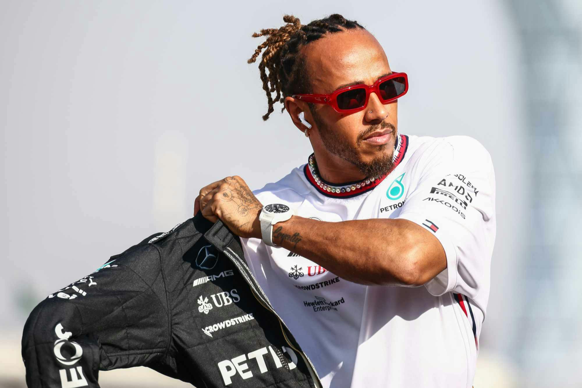 Lewis hamilton wears a black jacket, white T-shirt & red sunglasses