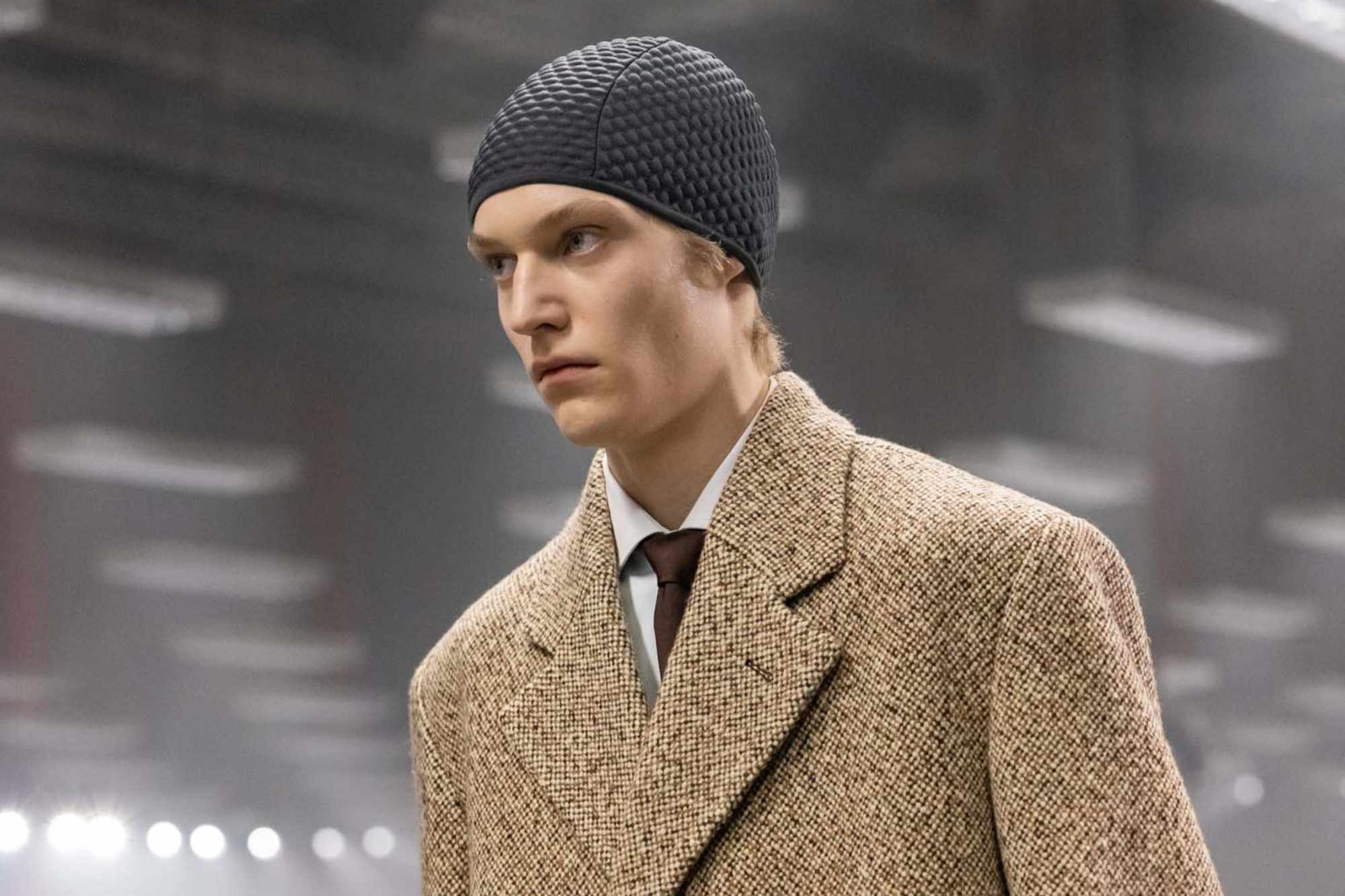 Models at Prada's Fall/Winter 2024 menswear runway show wear knit hoods and skullcaps