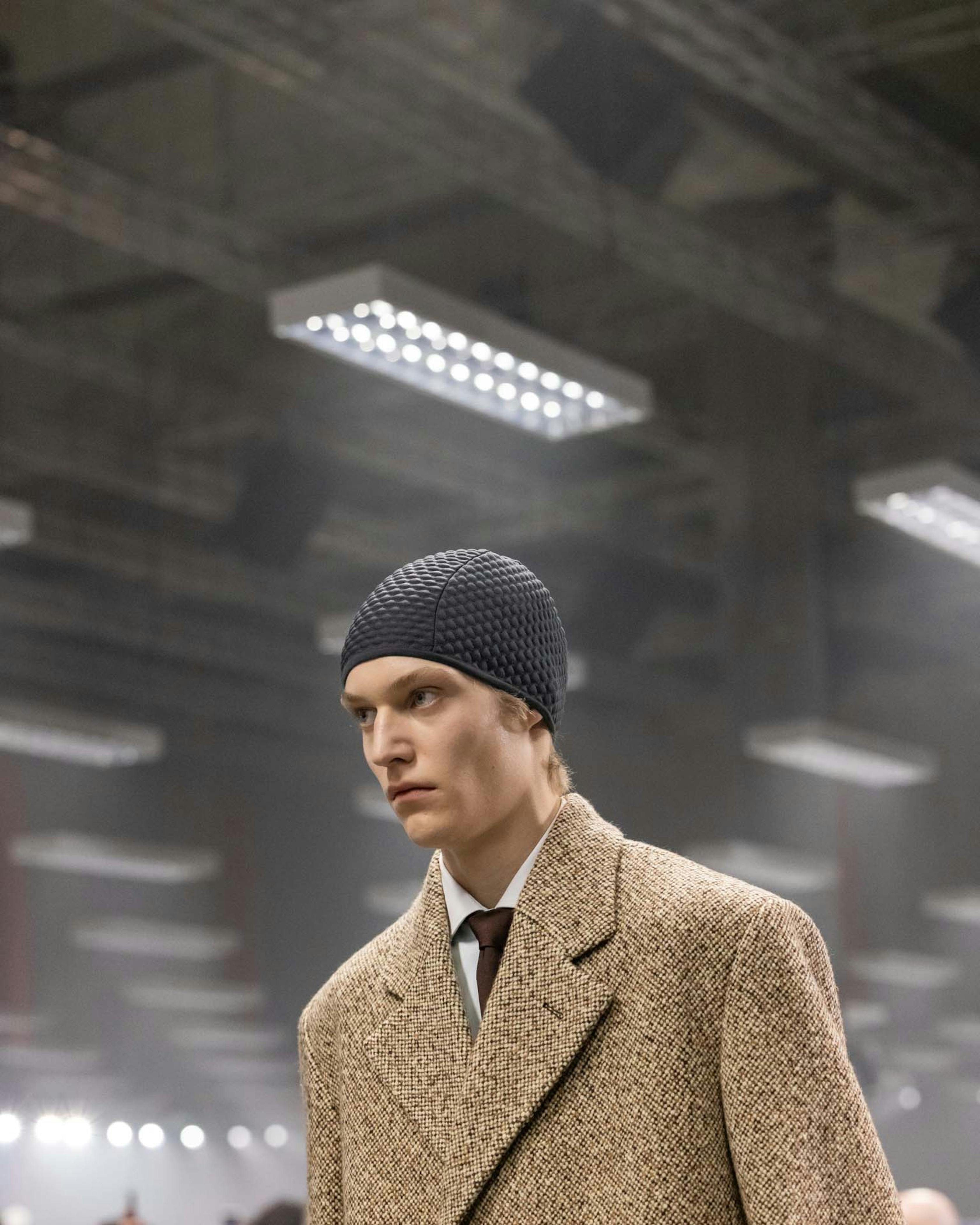 Models at Prada's Fall/Winter 2024 menswear runway show wear knit hoods and skullcaps