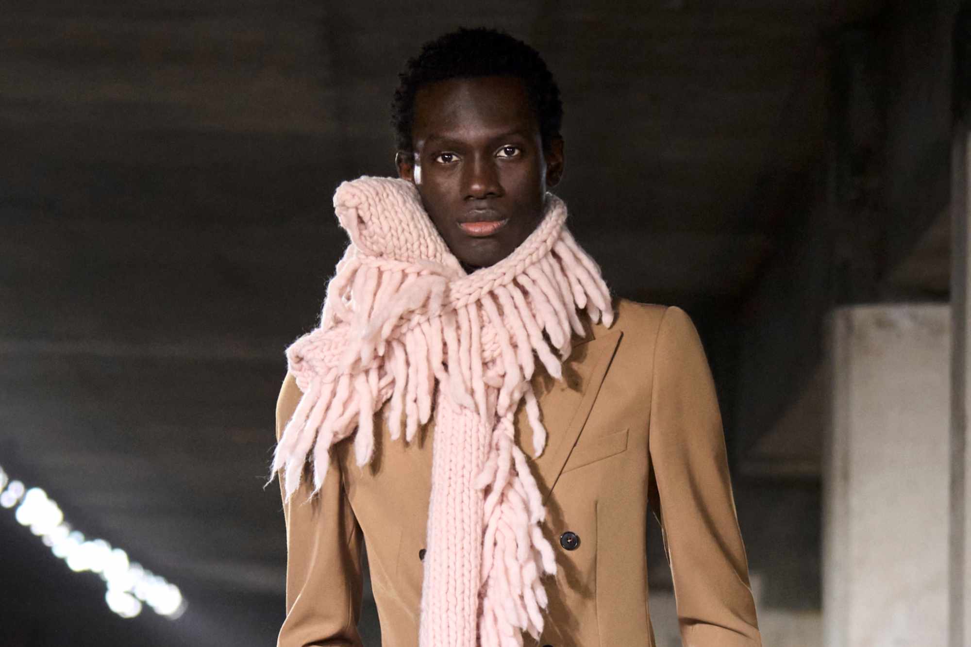 Dries Van Noten's Fall/Winter 2024 runway show with a model wearing a beige scarf, blazer and grey pants