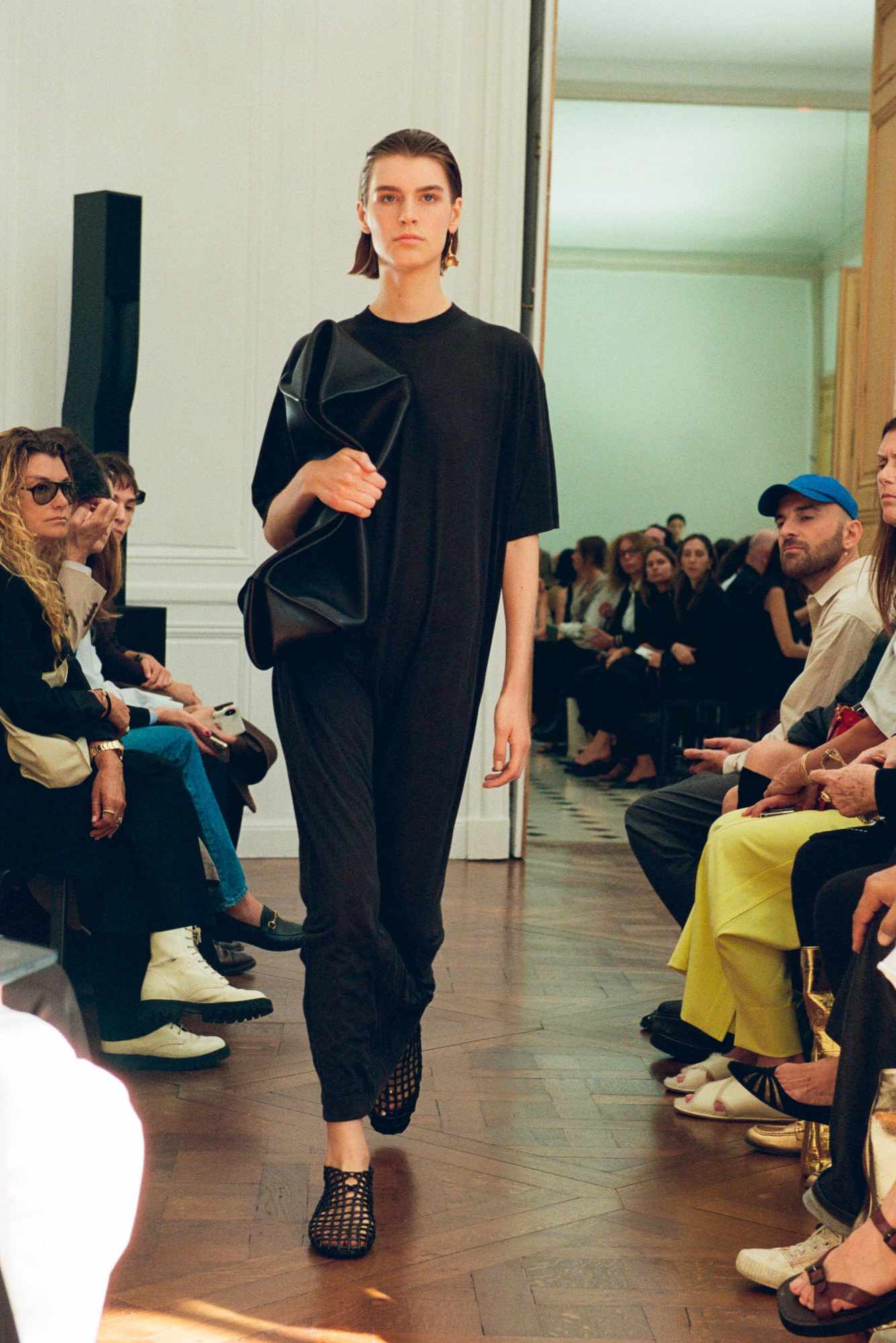 a model wears a black t-shirt and bag the row's fashion show