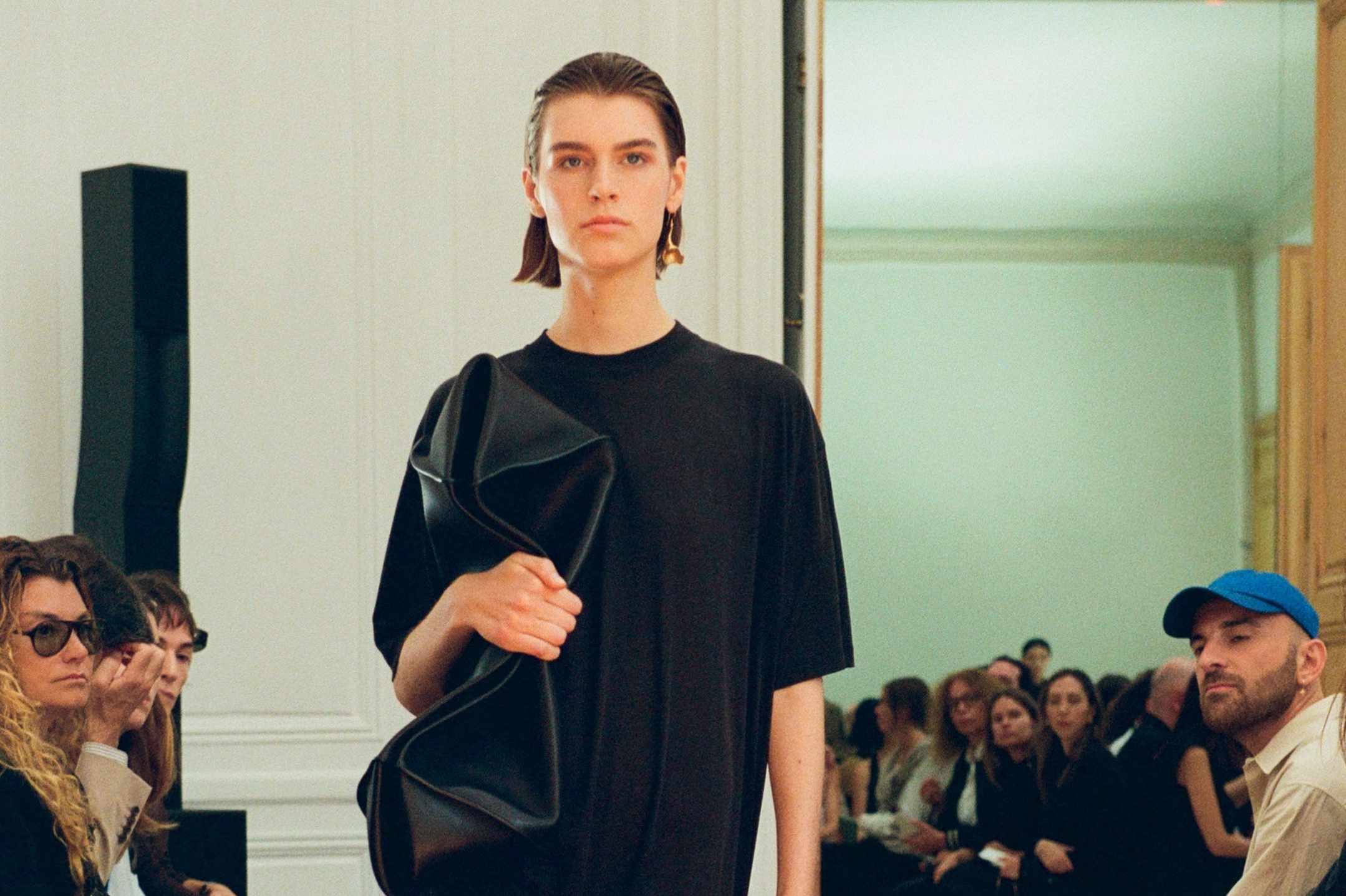 a model wears a black t-shirt and bag the row's fashion show