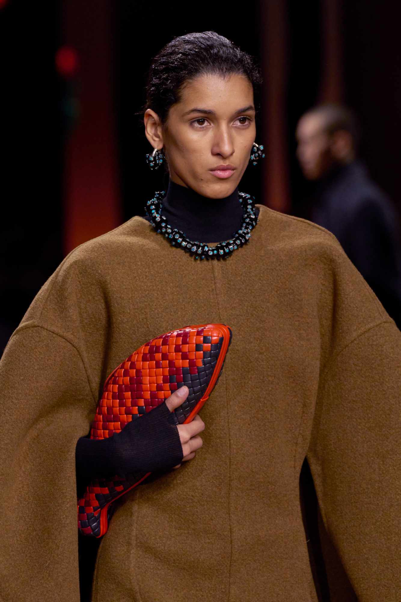 A model at Bottega Veneta's runway show holds a red and black leather fish bag