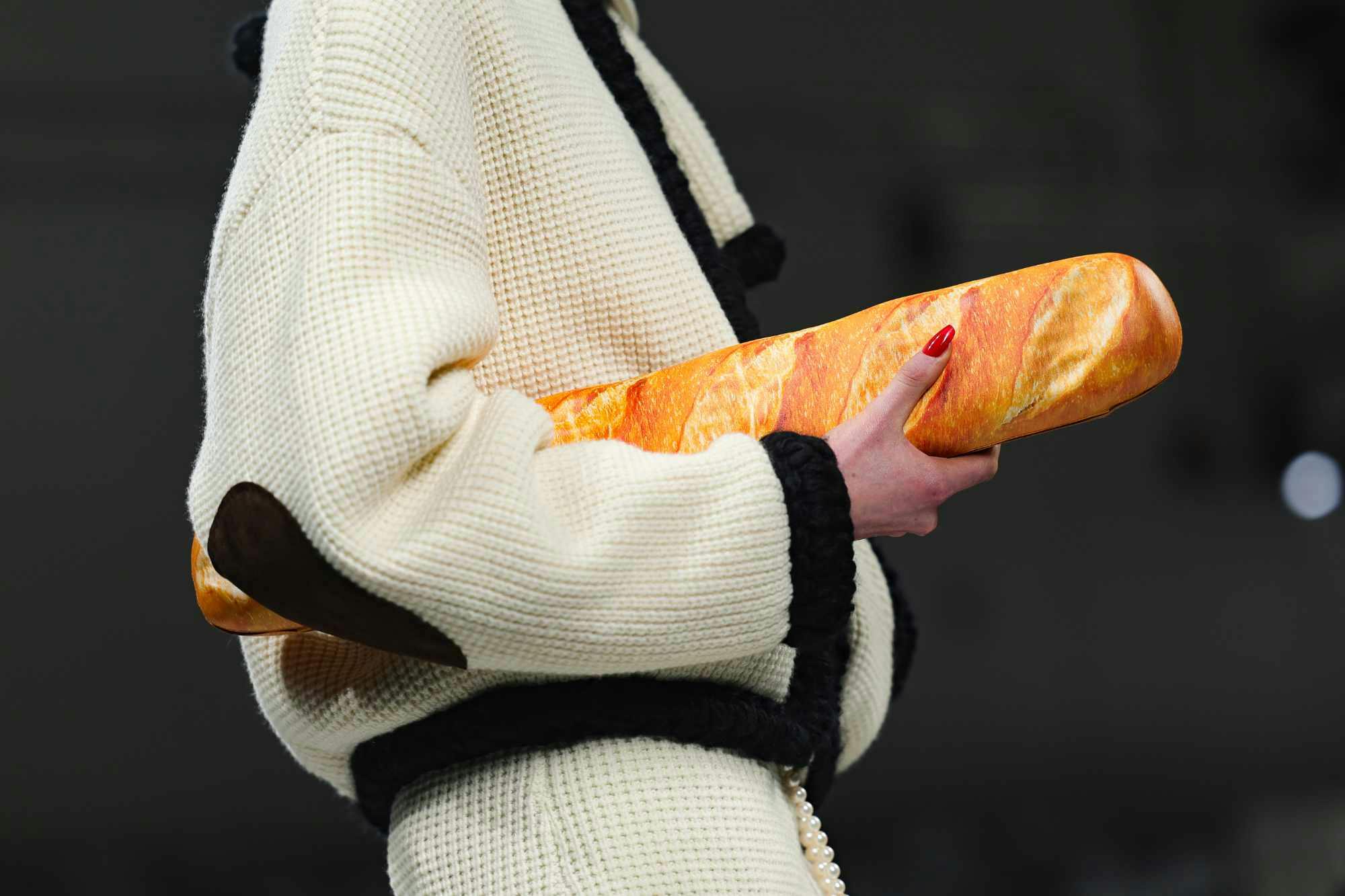 A model at Moschino's runway show holds a baguette-shaped handbag