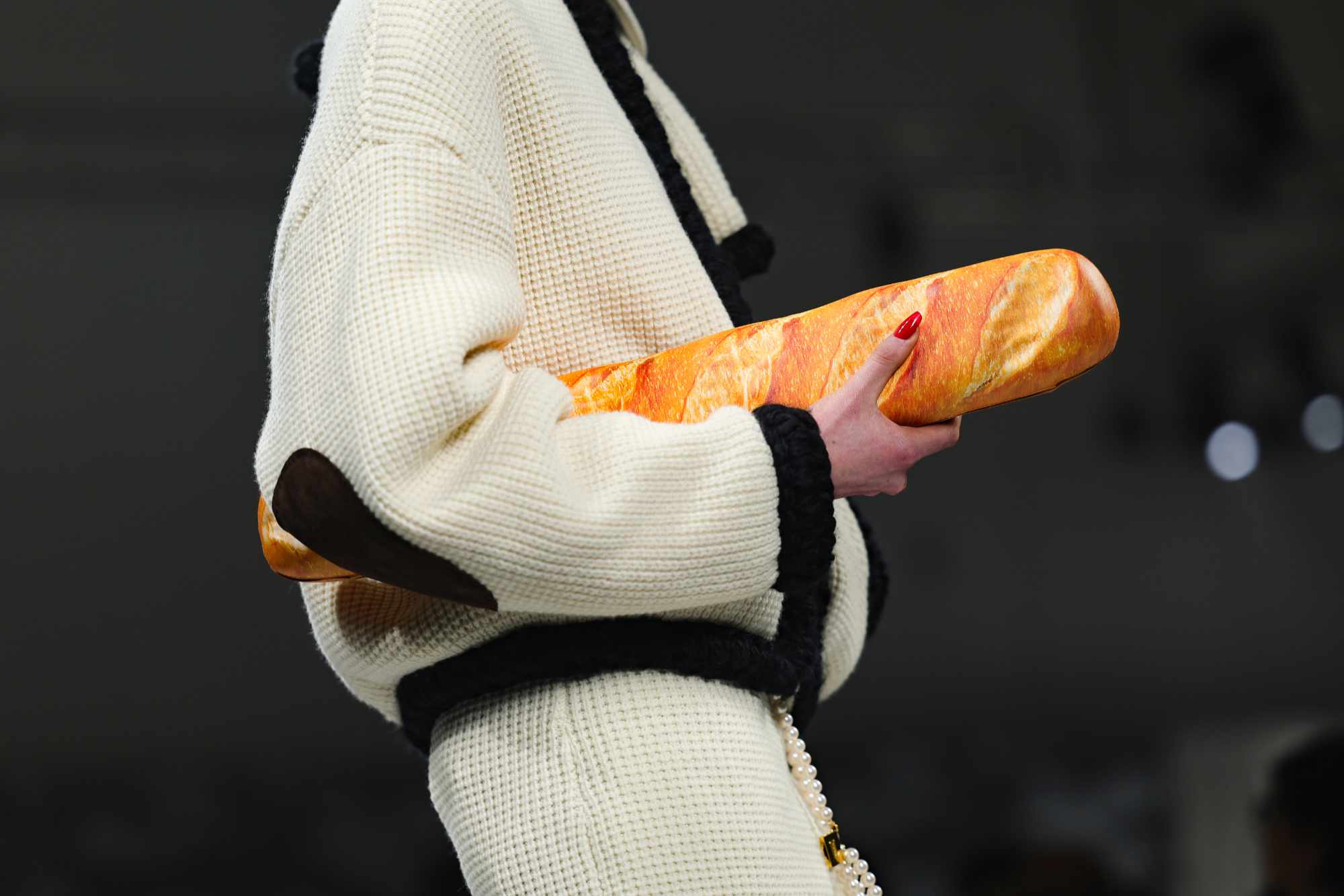 A model at Moschino's runway show holds a baguette-shaped handbag