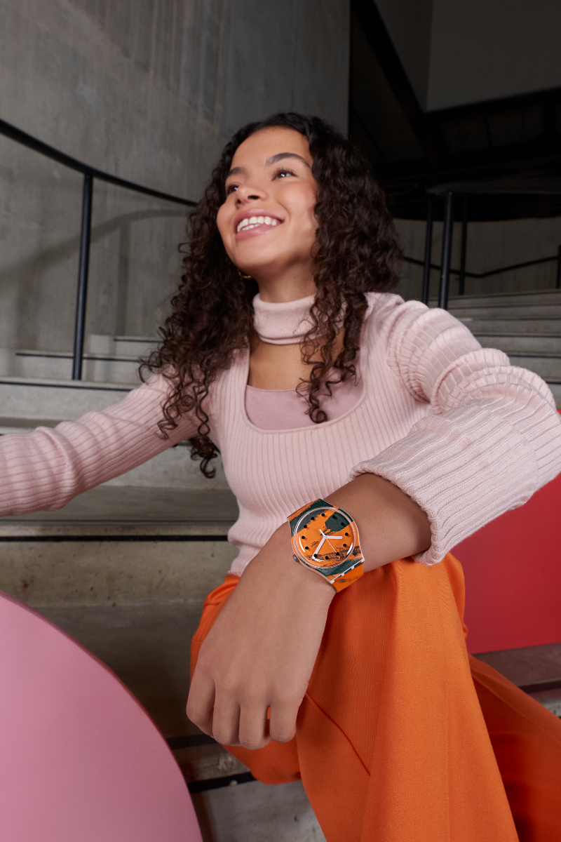 Woman smiles wearing an orange swatch and matching outfit