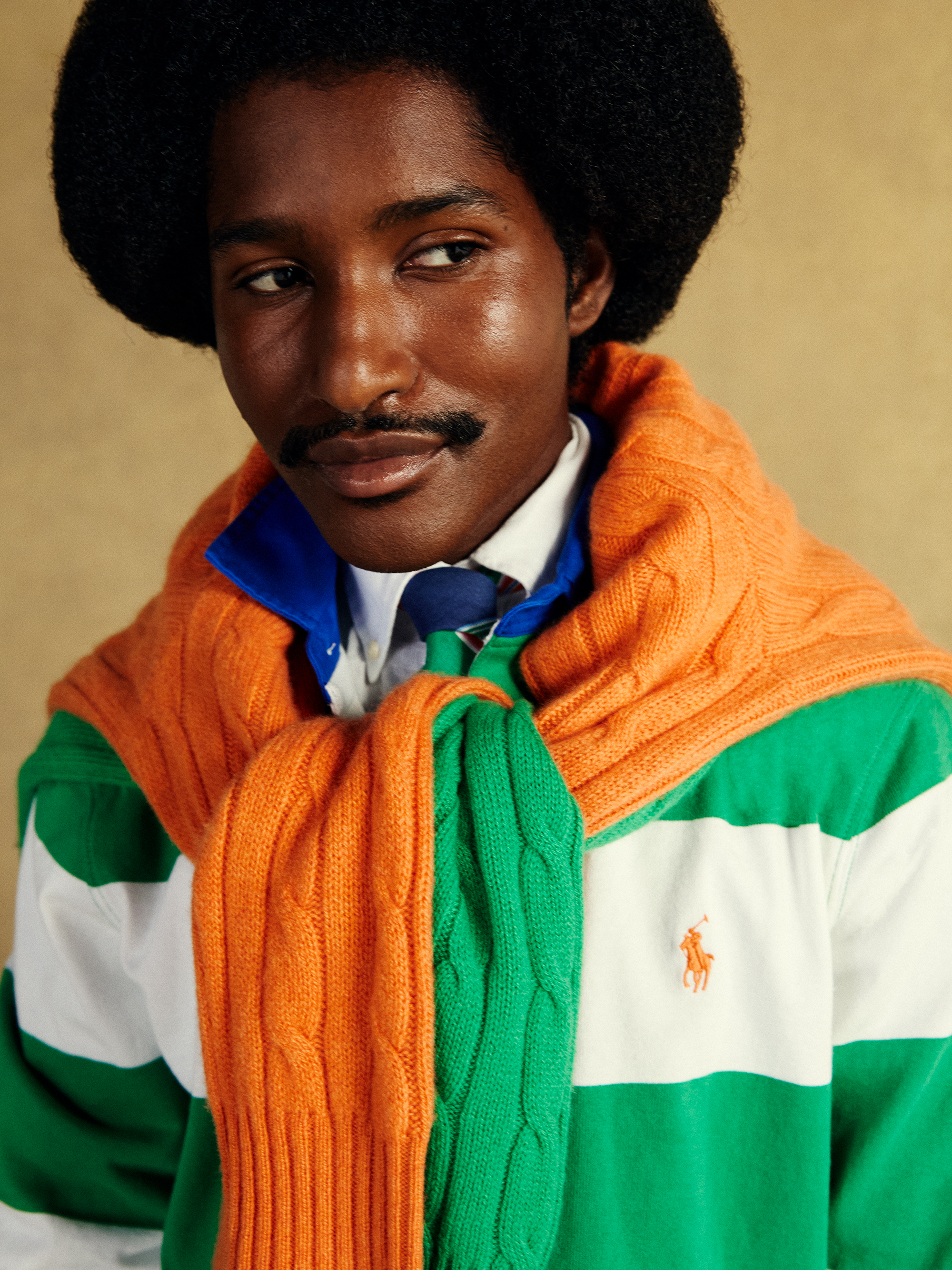 Close-up of model smiling wearing preppy green and orange jumpers