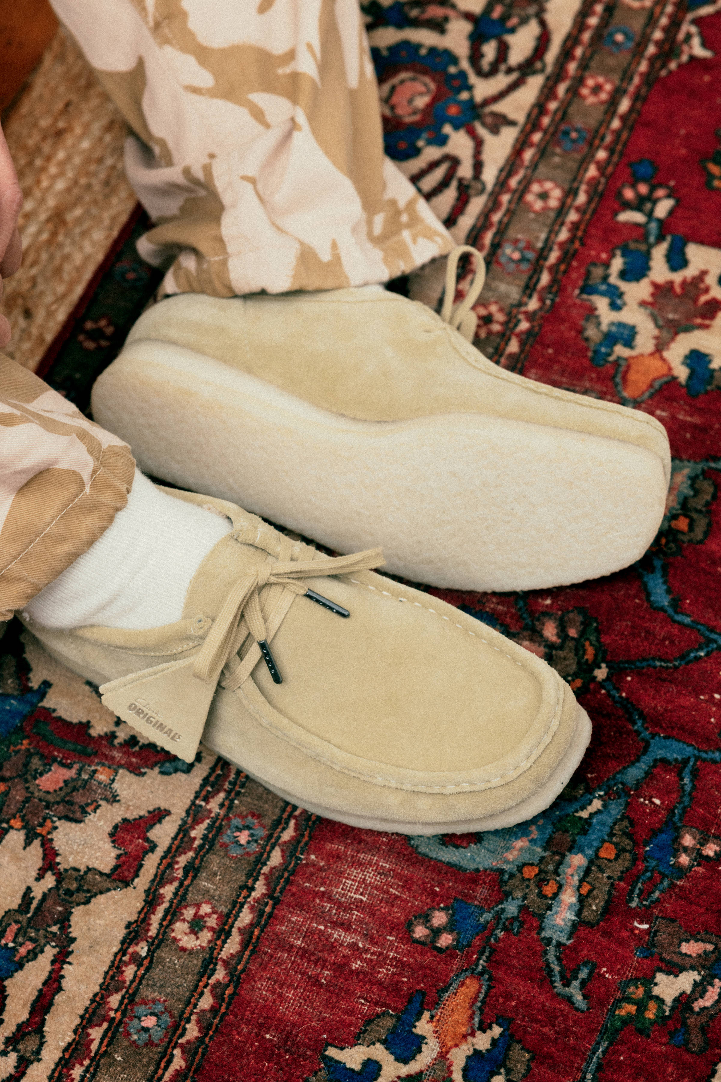 Close-up of a person wearing Clarks Originals on a rug floor