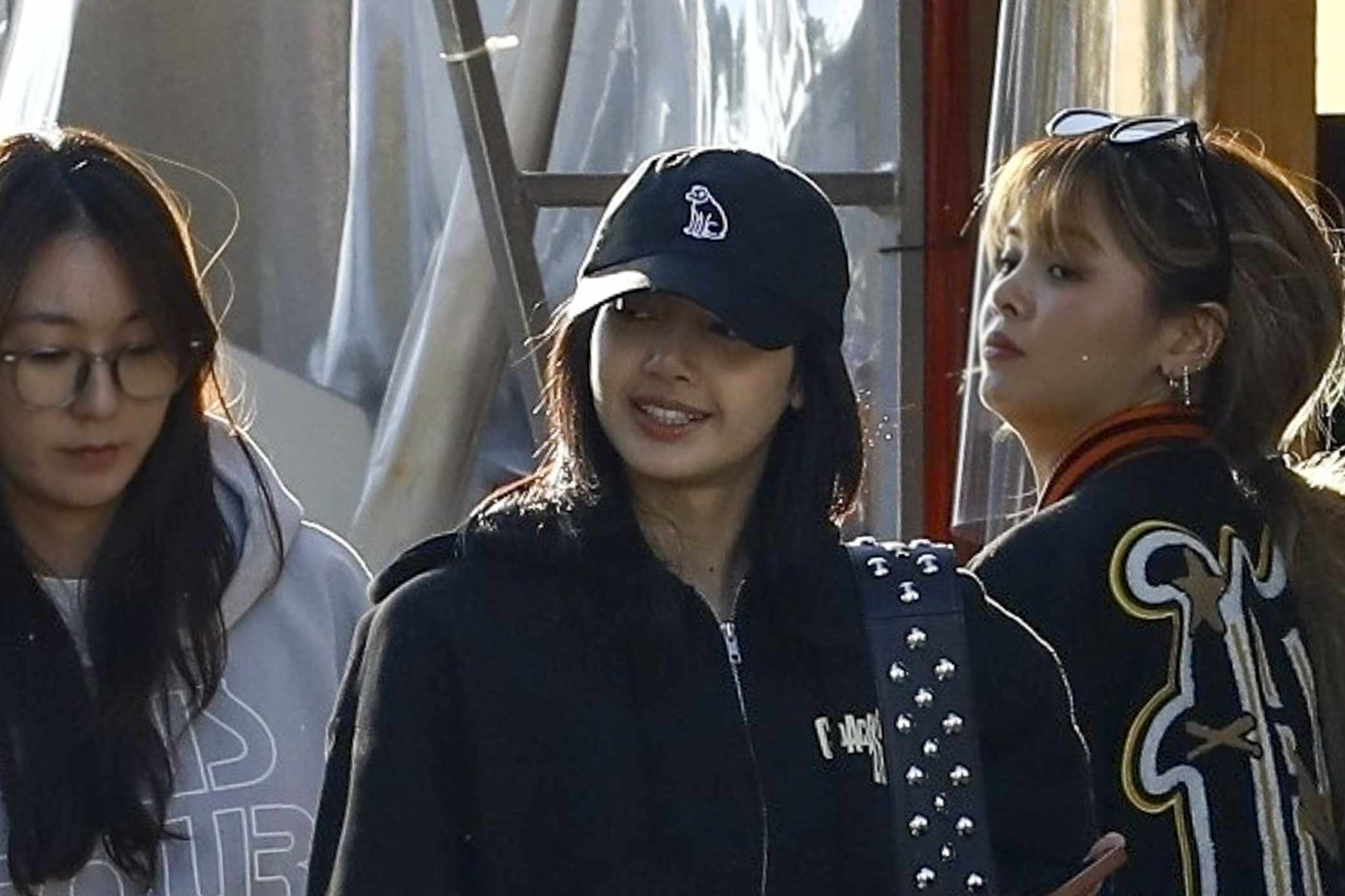 Lisa from BLACKPINK wears a black cap, Coachella 2024 hoodie, blue jeans, and white sneakers in beverly hills