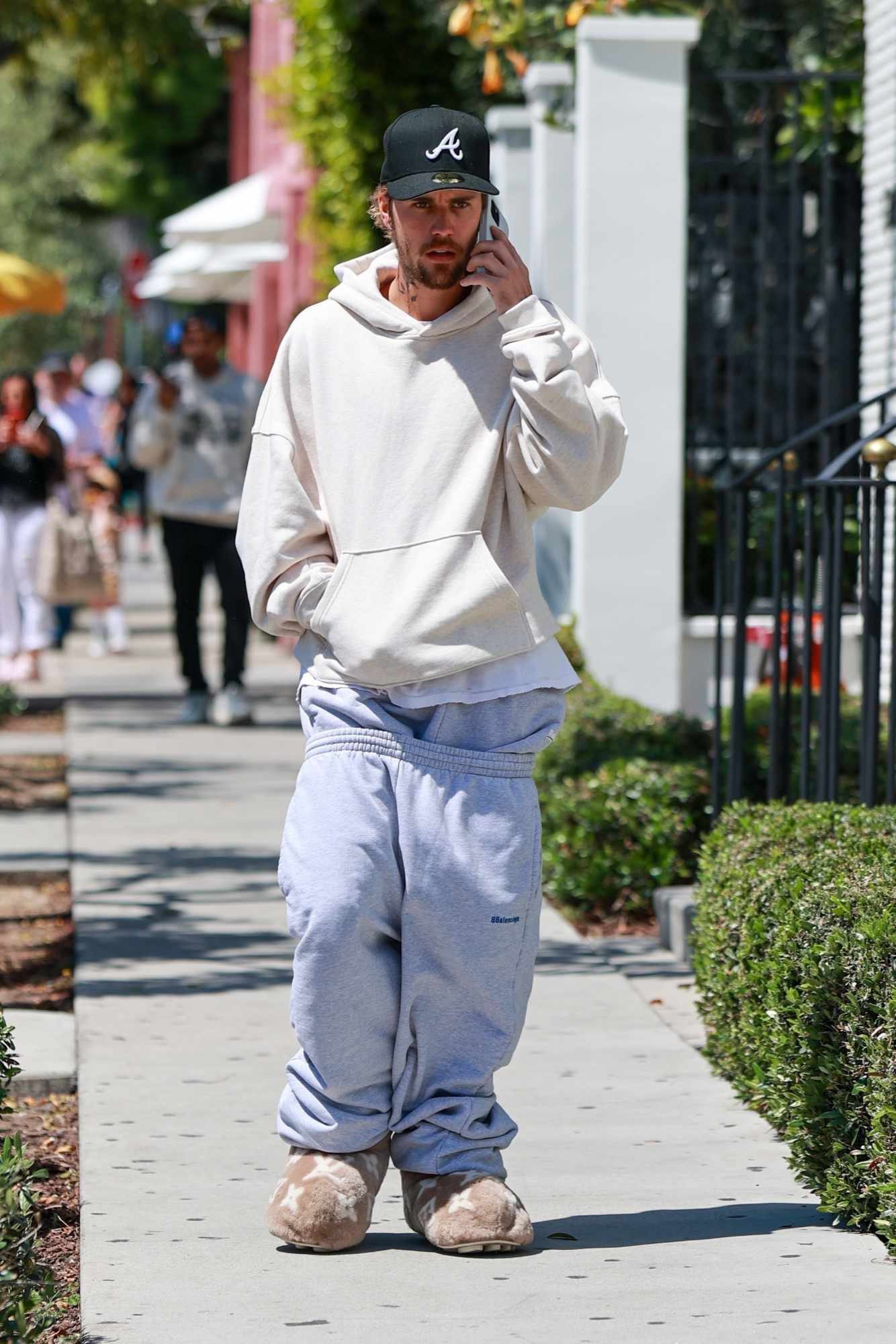 Justin Bieber wears a yellow hoodie, two pairs of grey sweatpants, brown louis vuitton slippers