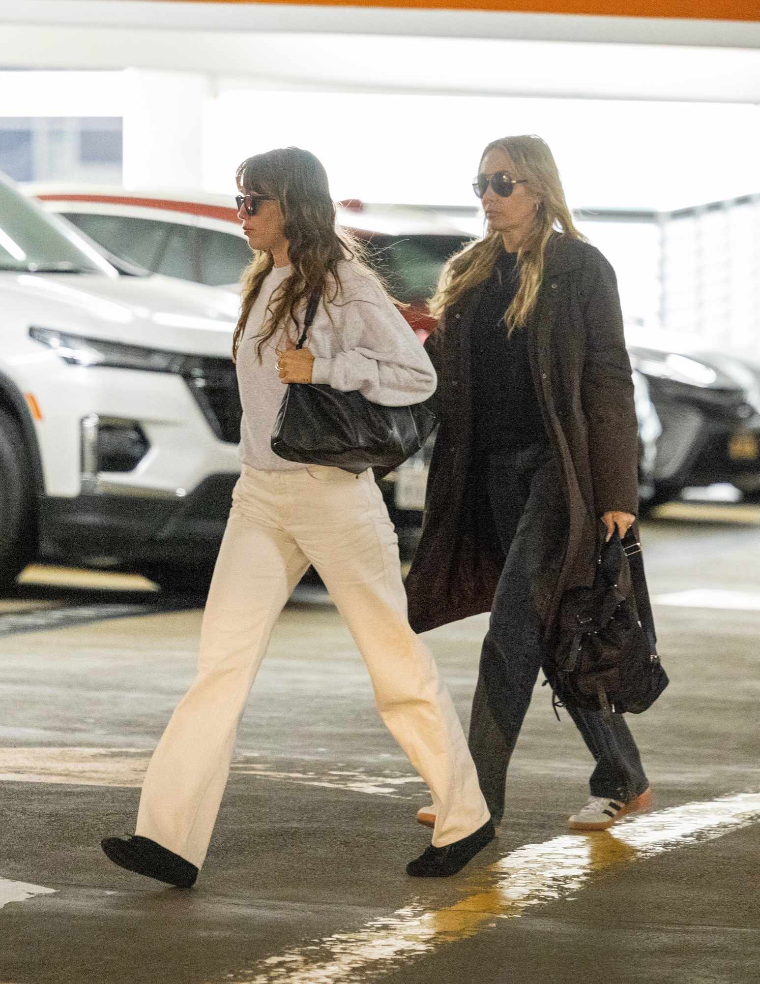 Miley Cyrus and mother Tish seen wearing a grey sweater, white jeans, black shoes, big sunglasses and black handbag