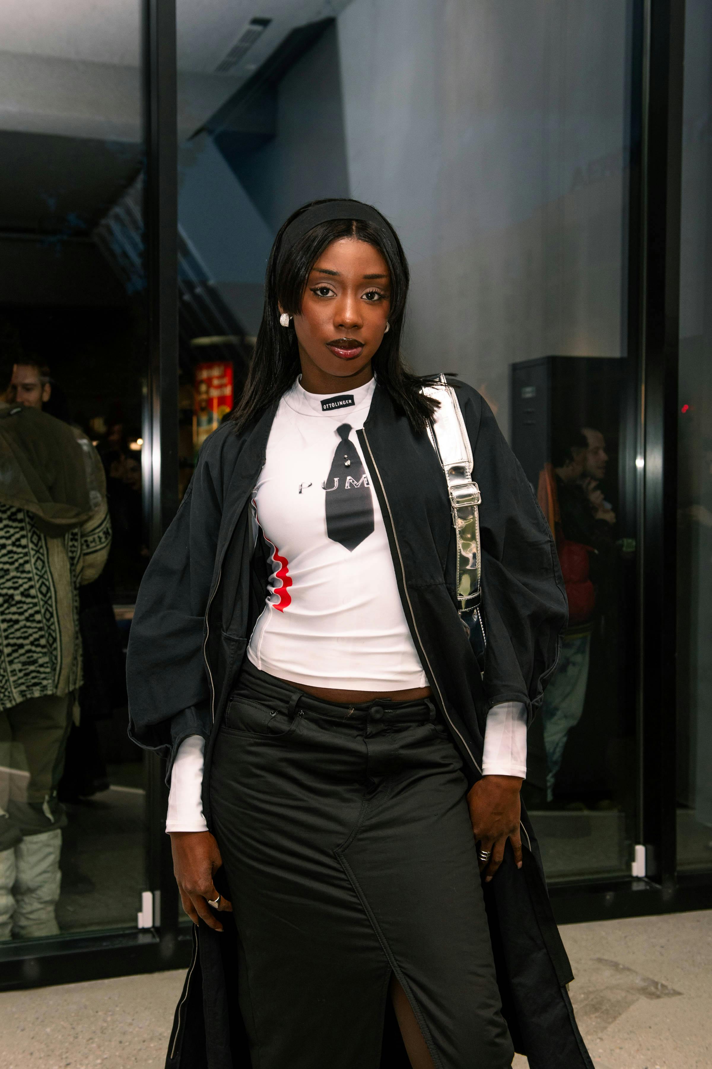 Woman poses at an event wearing a bodysuit and a silver bag