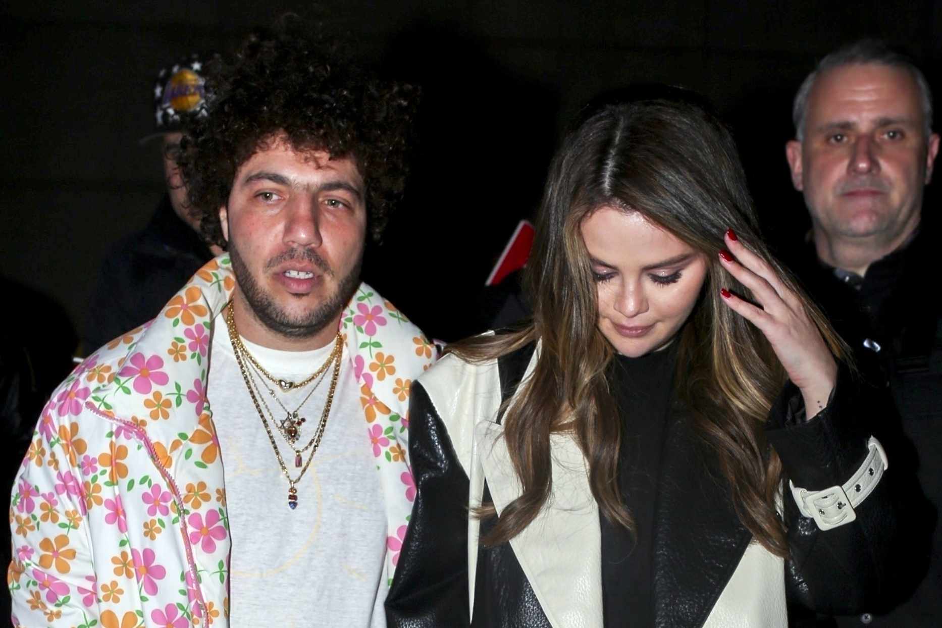 Benny Blanco wearing a floral puffer jacket with girlfriend Selena Gomez wearing a black coat