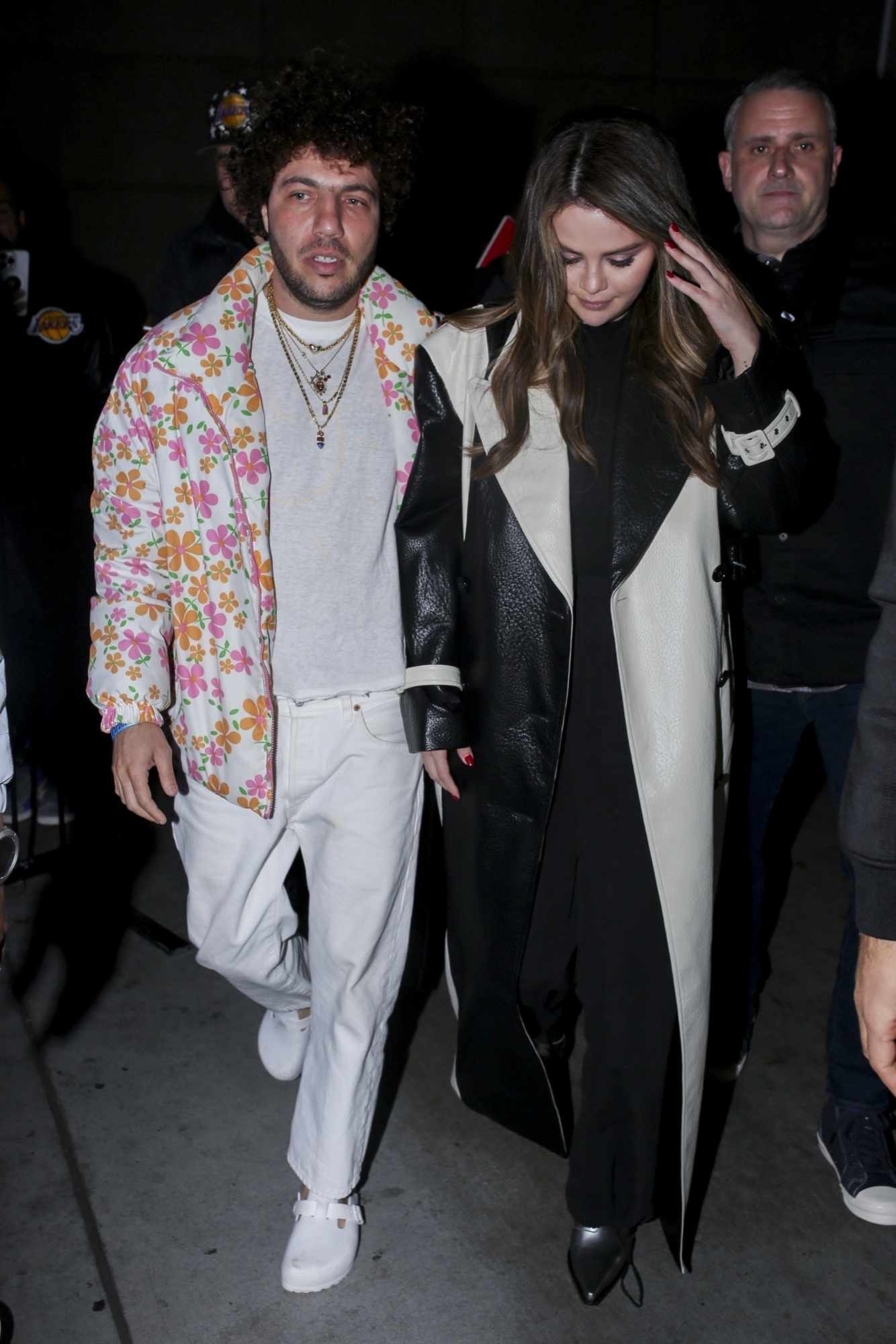 Benny Blanco wearing a floral puffer jacket with girlfriend Selena Gomez wearing a black coat