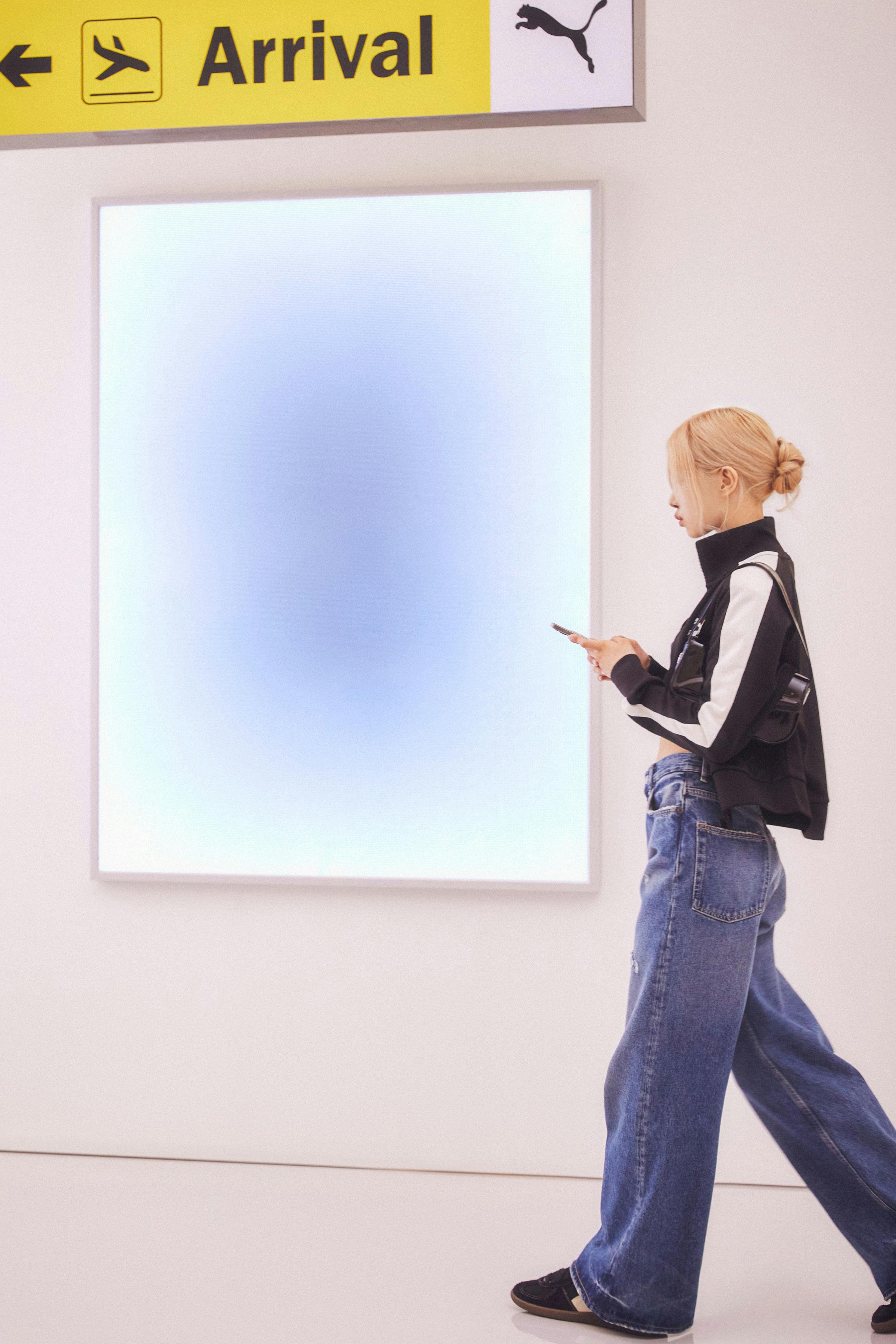 Woman looking at a phone walking through airport arrivals