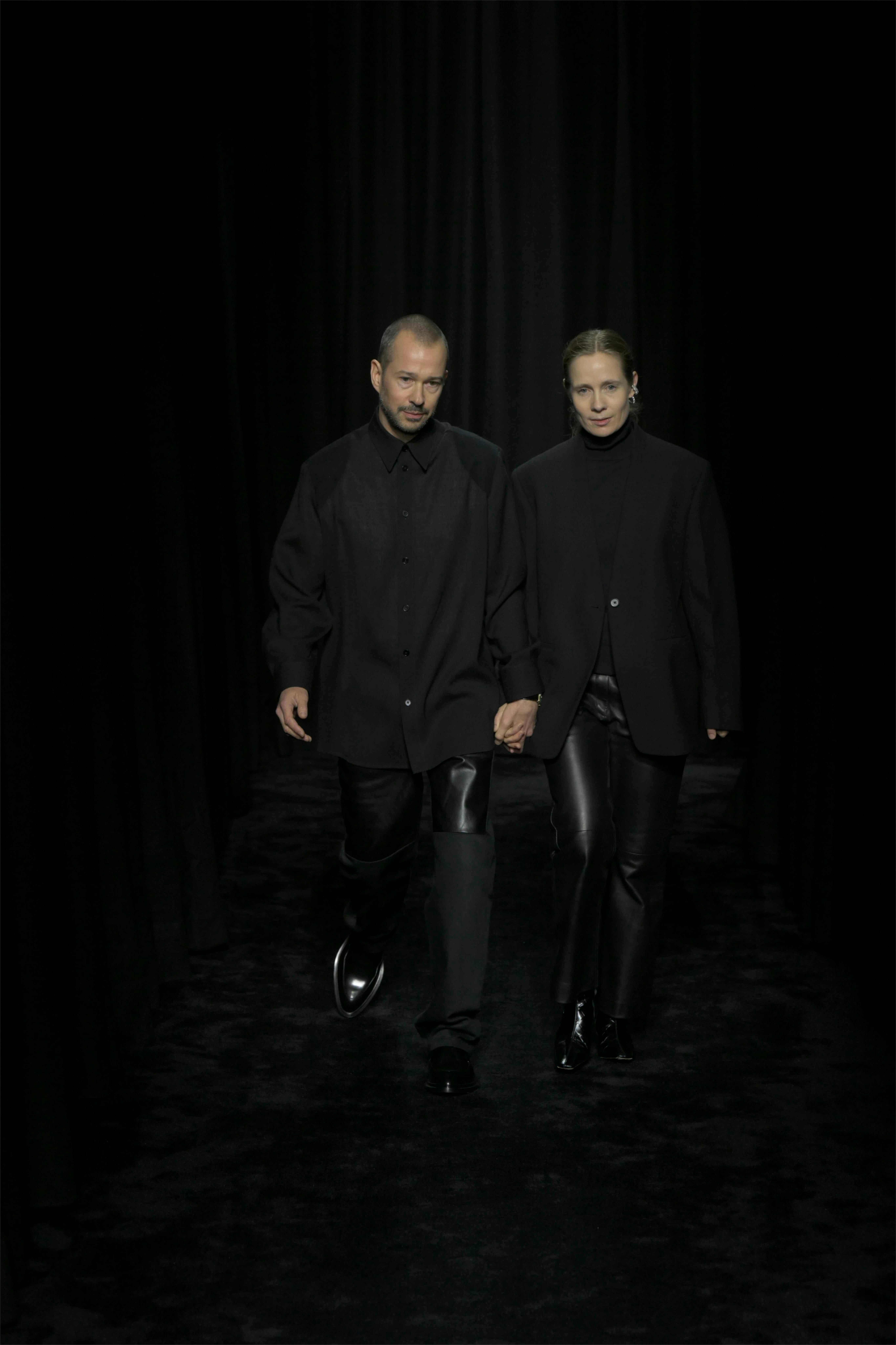 jil sander creative directors luke and lucie meier hold hands at their fall/winter 2025 fashion show