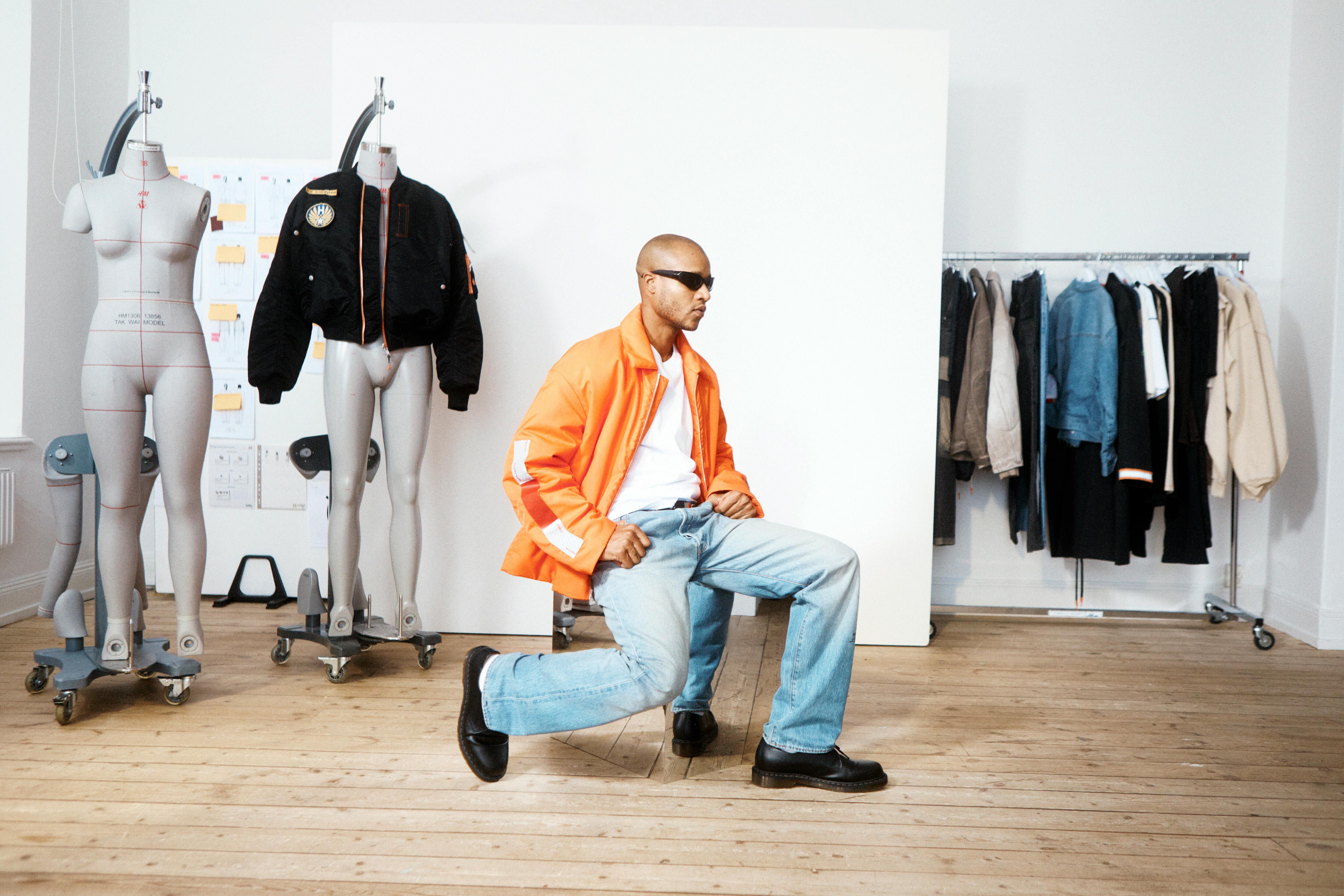 Heron Preston & H&M's menswear directors reveal the H2 collaboration, sitting in a room with mannequins and clothes on racks