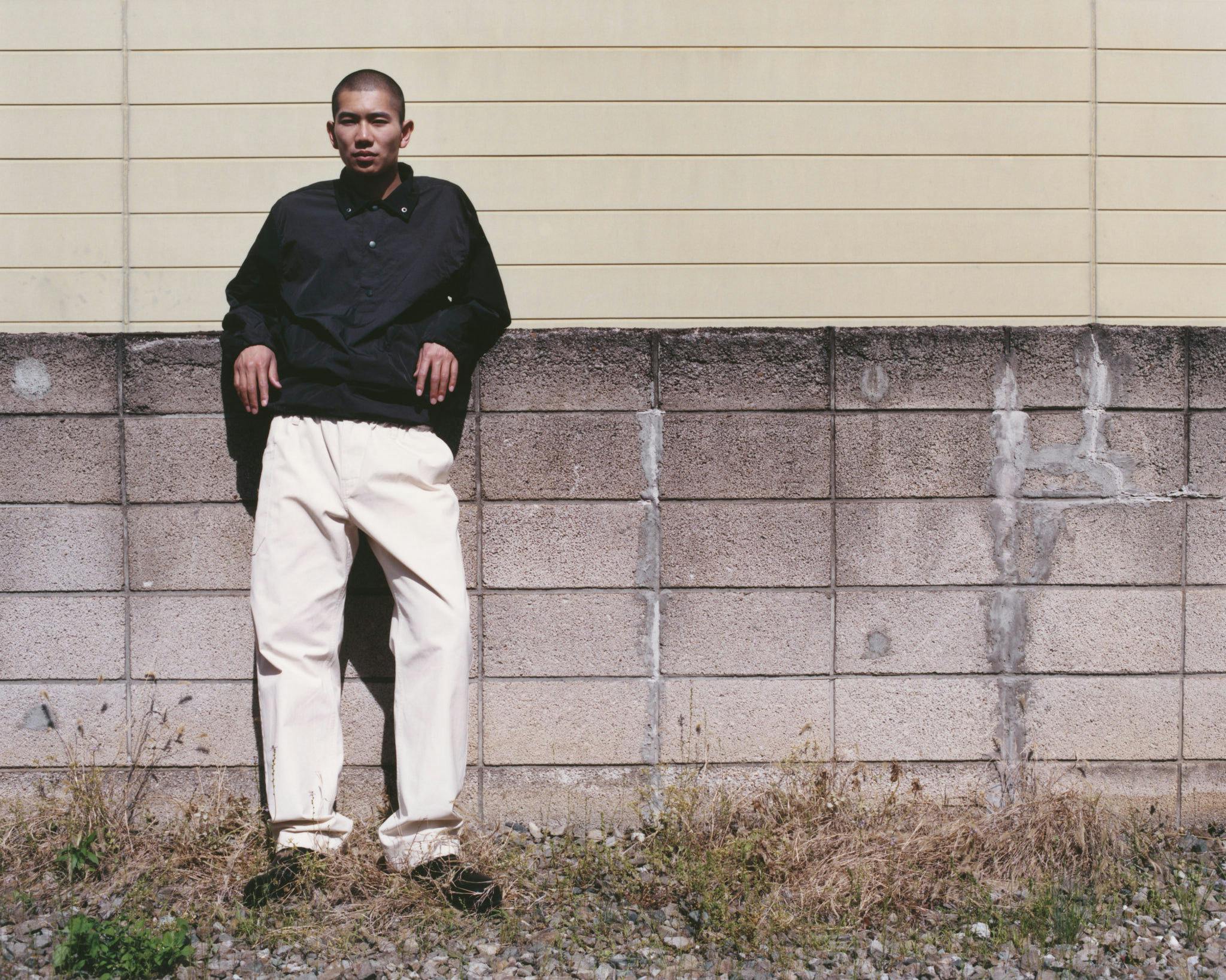 Model in Morrow outerwear standing against a sunlit concrete wall