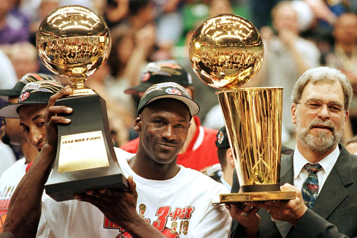 Michael Jordan (L) holds the NBA Finals Most Valuable Player trophy and former Chicago Bulls head coach Phil Jackson holds the NBA champions Larry O'Brian trophy 14 June after winning game six of the NBA Finals with the Utah Jazz at the Delta Center in Salt Lake City, UT.