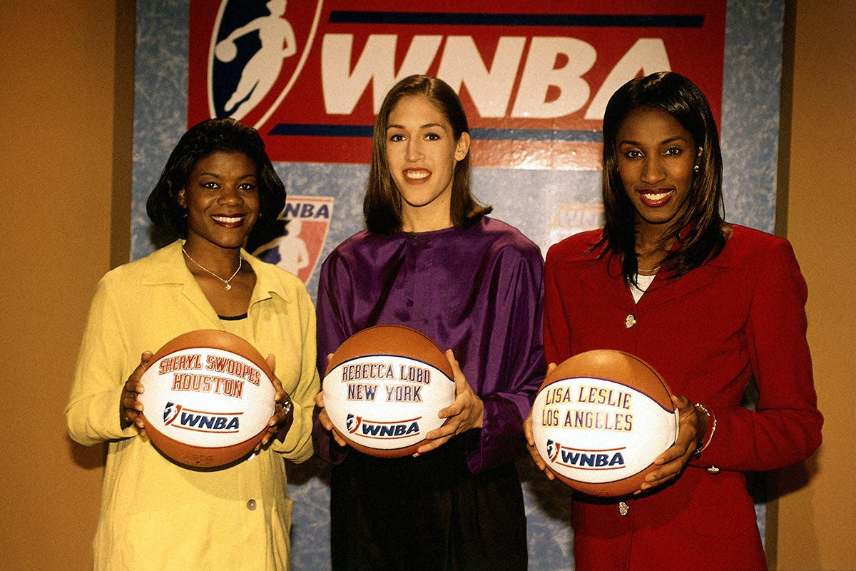 (L-R) Sheryl Swoopes, Rebecca Lobo, and Lisa Leslie hold basketballs designating the new WNBA teams to which they were assigned on January 22, 1997, in Secaucus, N.J. Swoopes was assigned to Houston, Lobo to New York, and Leslie to Los Angeles