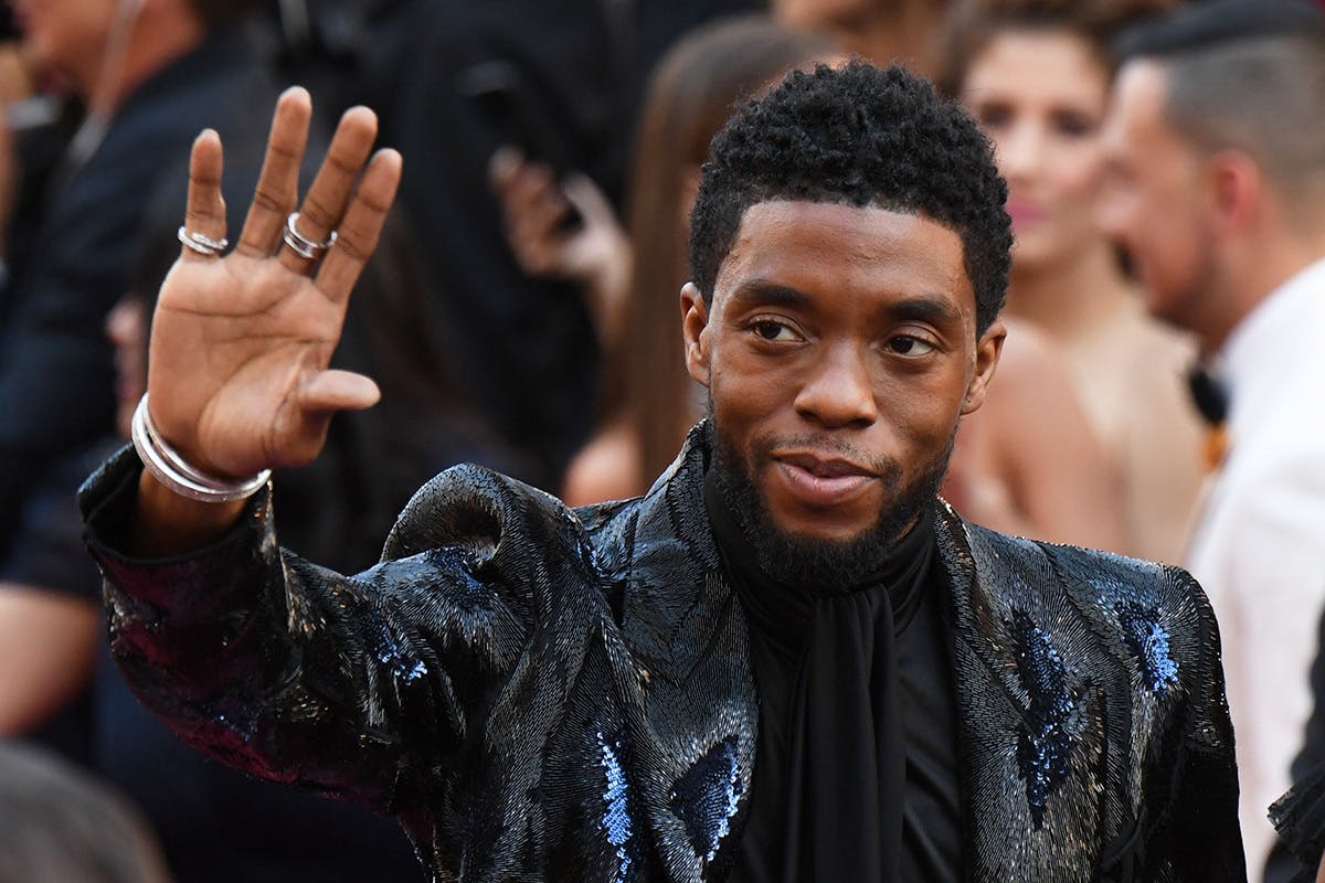 Chadwick Boseman waves at an event